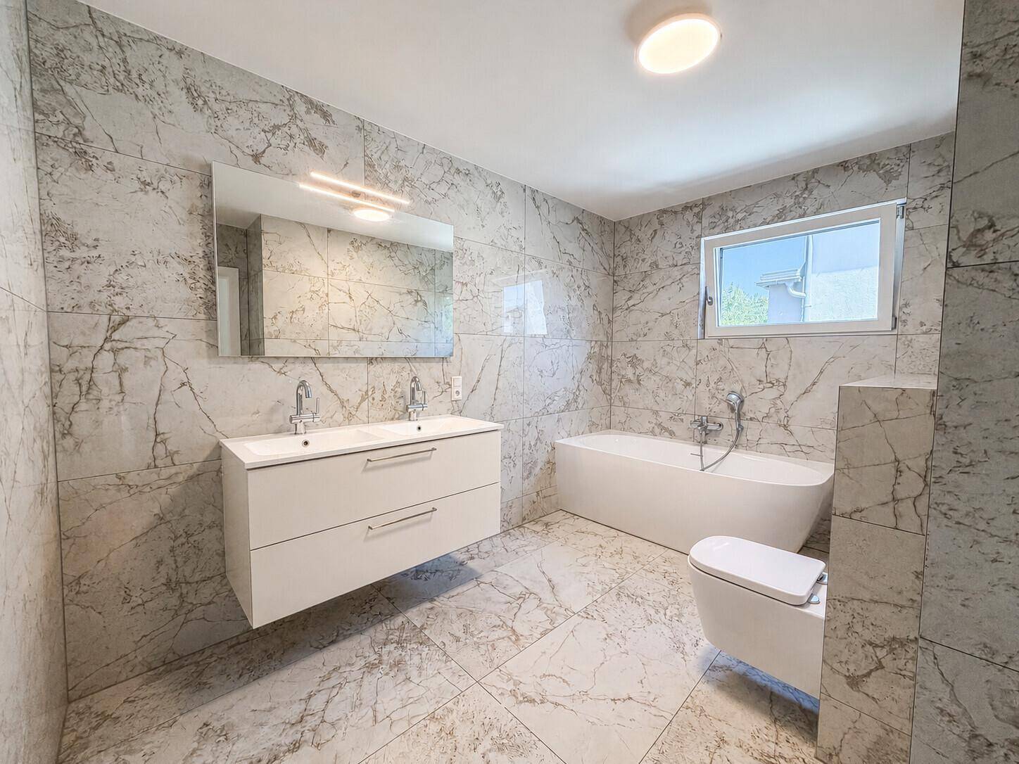 Luxuriöses Badezimmer mit Marmorfliesen, Doppelwaschbecken und freistehender Badewanne.