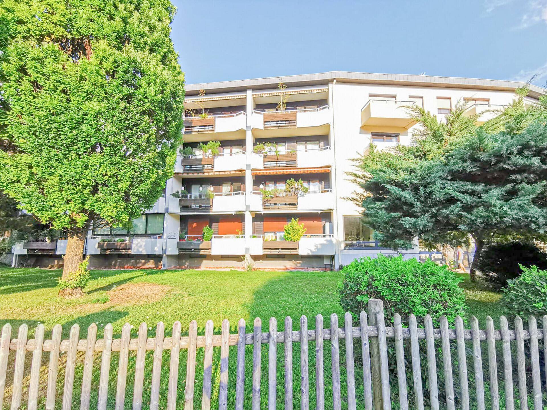 Mehrfamilienhaus mit Balkonen und gepflegter Grünfläche im Vordergrund.