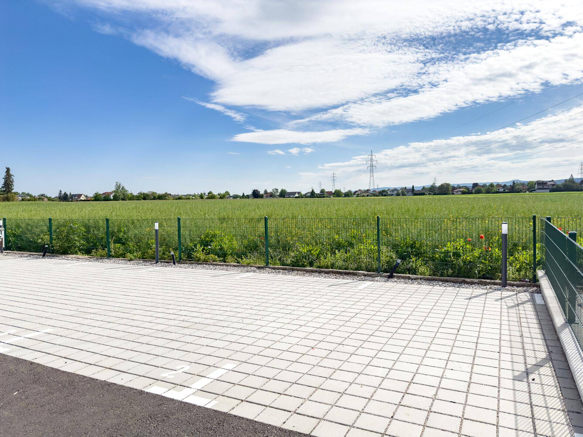 Außenparkplätze mit Blick auf weite grüne Felder und den Horizont.