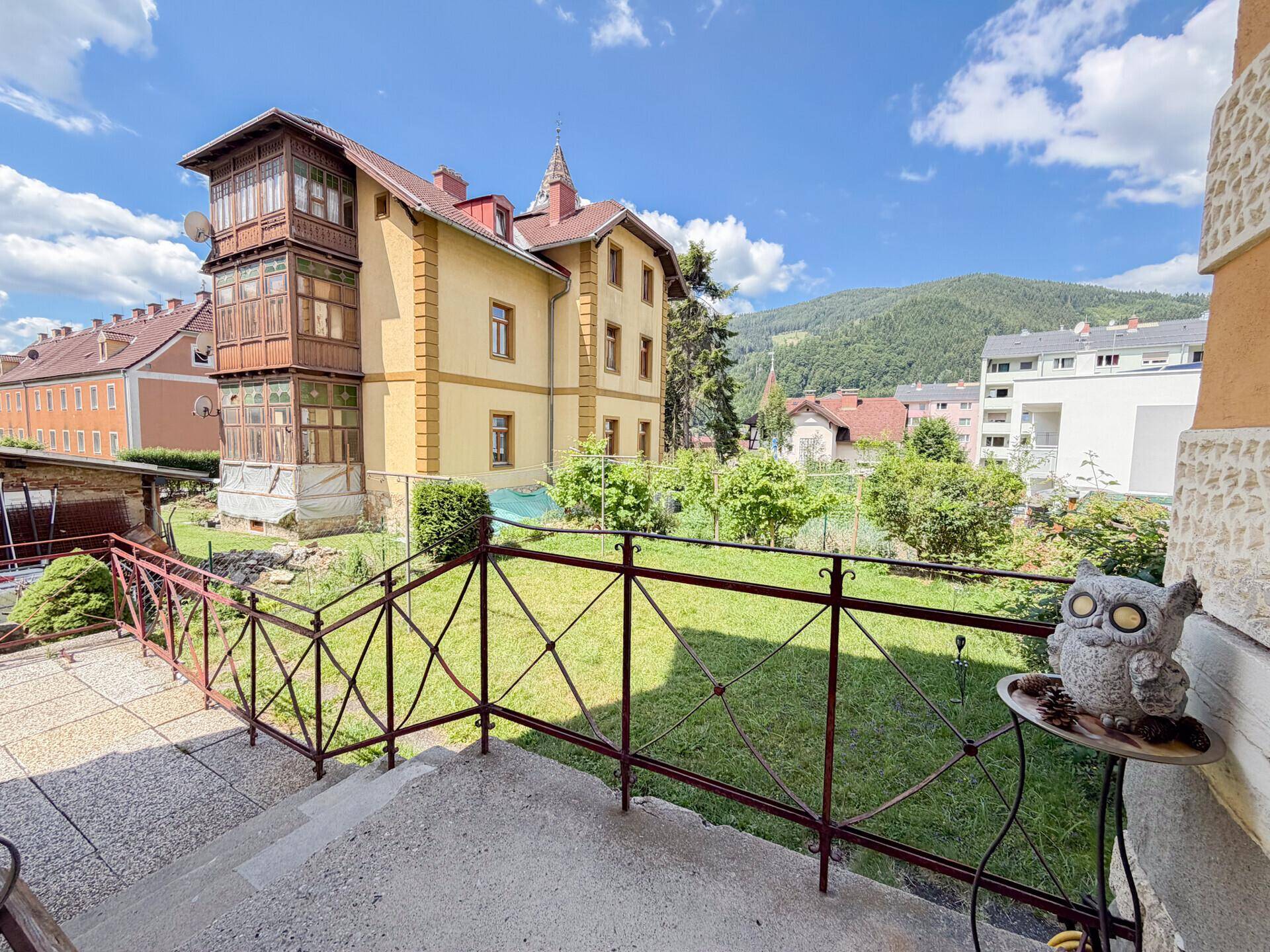 Terrasse mit schmiedeeisernem Geländer, Blick auf den Garten und die malerische Berglandschaft.