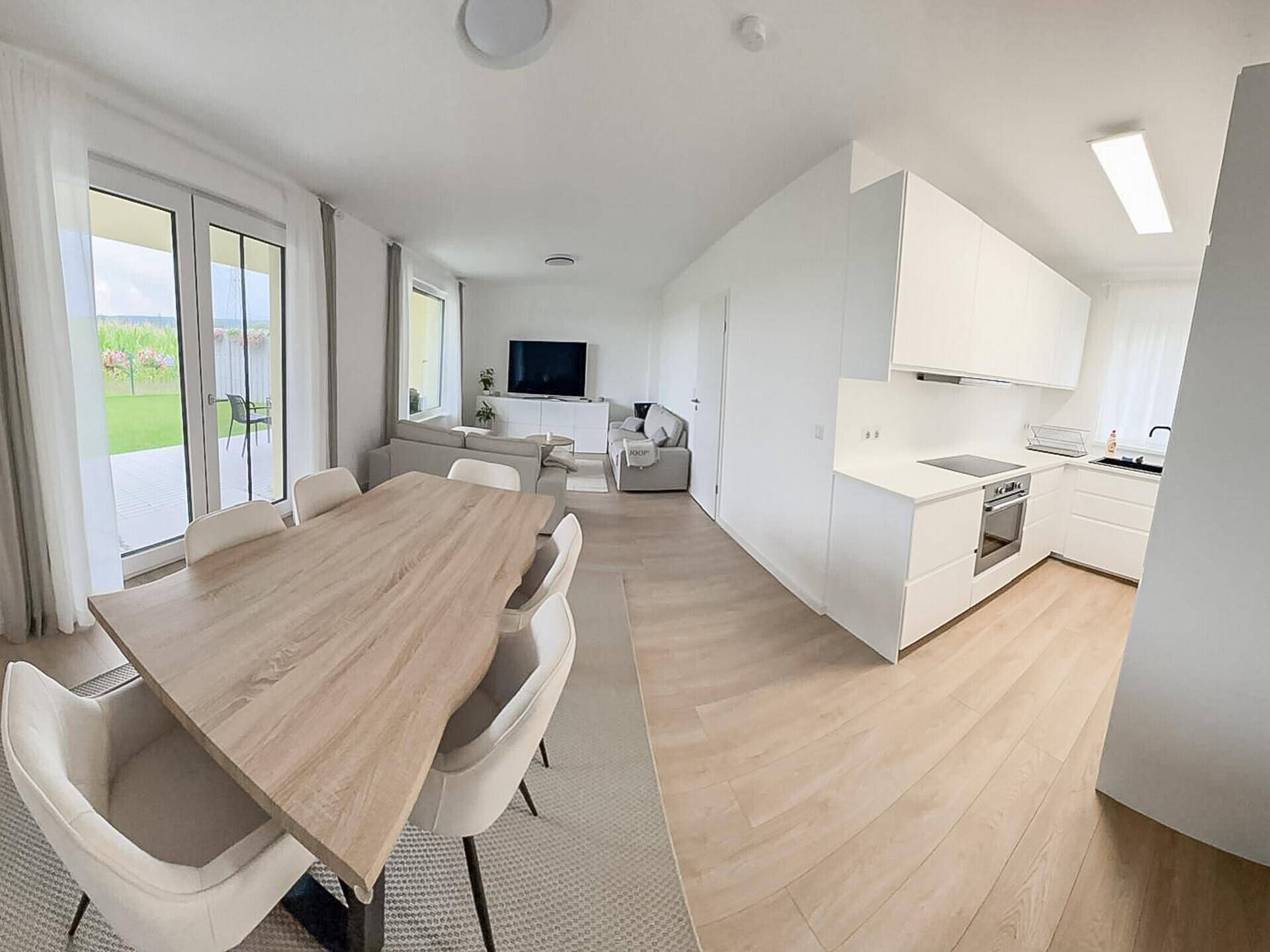 Offener Wohn-Essbereich mit integrierter Küche, Holzboden und viel Tageslicht.