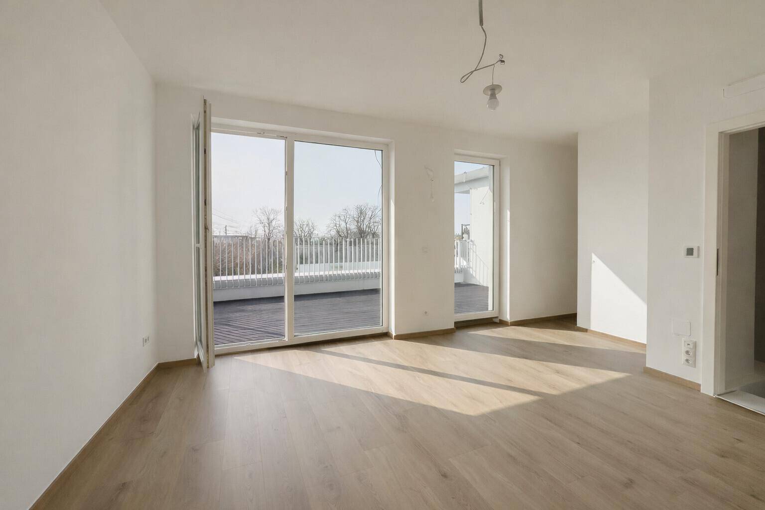 Heller Raum mit Holzboden und direktem Zugang zu einer großzügigen Dachterrasse.