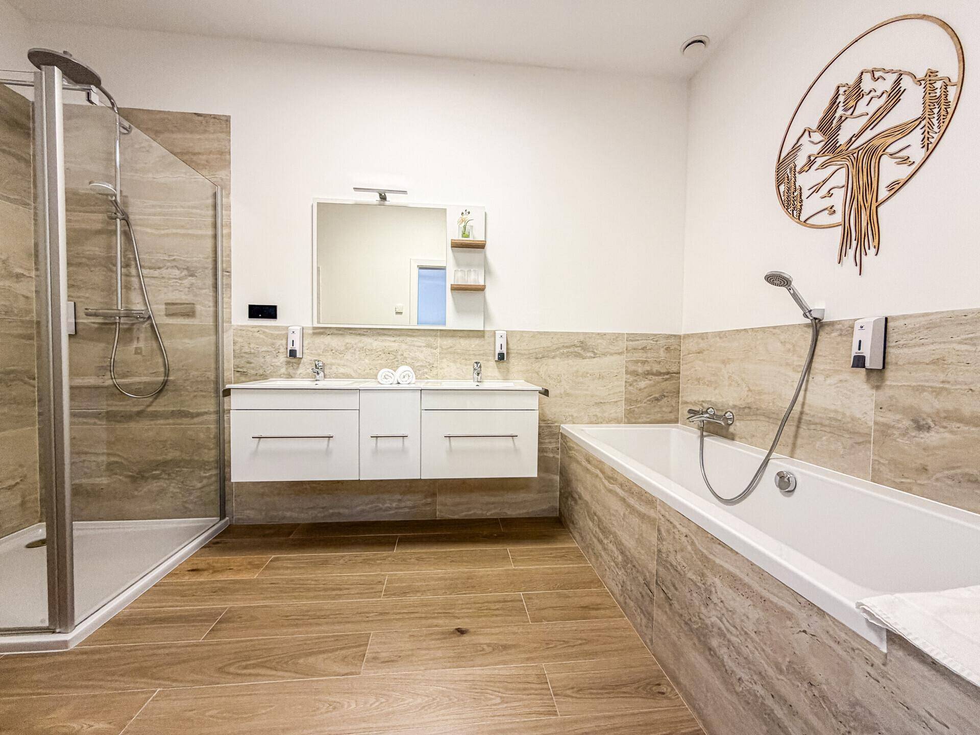 Geräumiges Badezimmer mit Doppelwaschbecken, Badewanne und großer begehbarer Duschkabine.