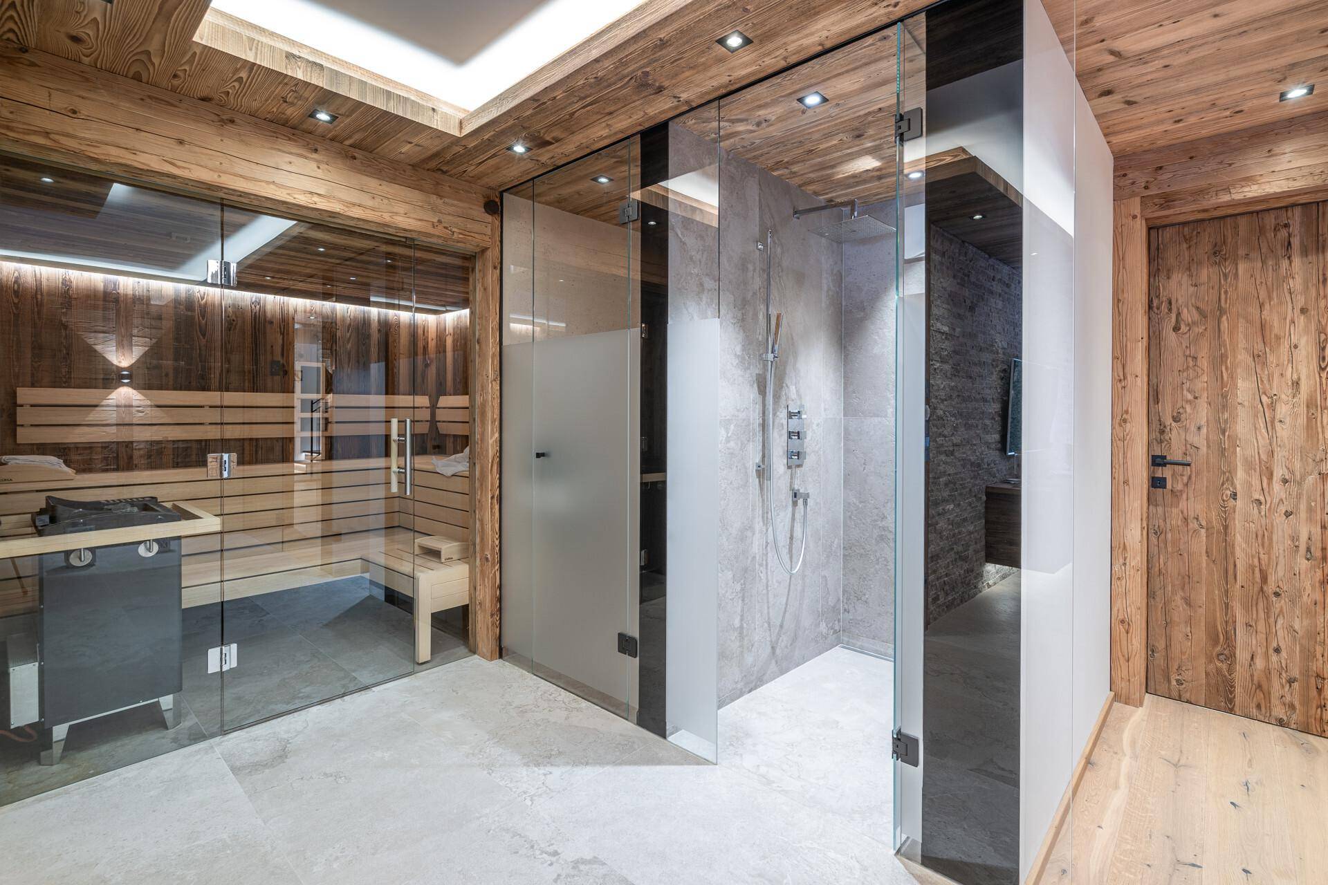 Exklusiver Wellnessbereich mit moderner Sauna, begehbarer Dusche und Holzakzenten.