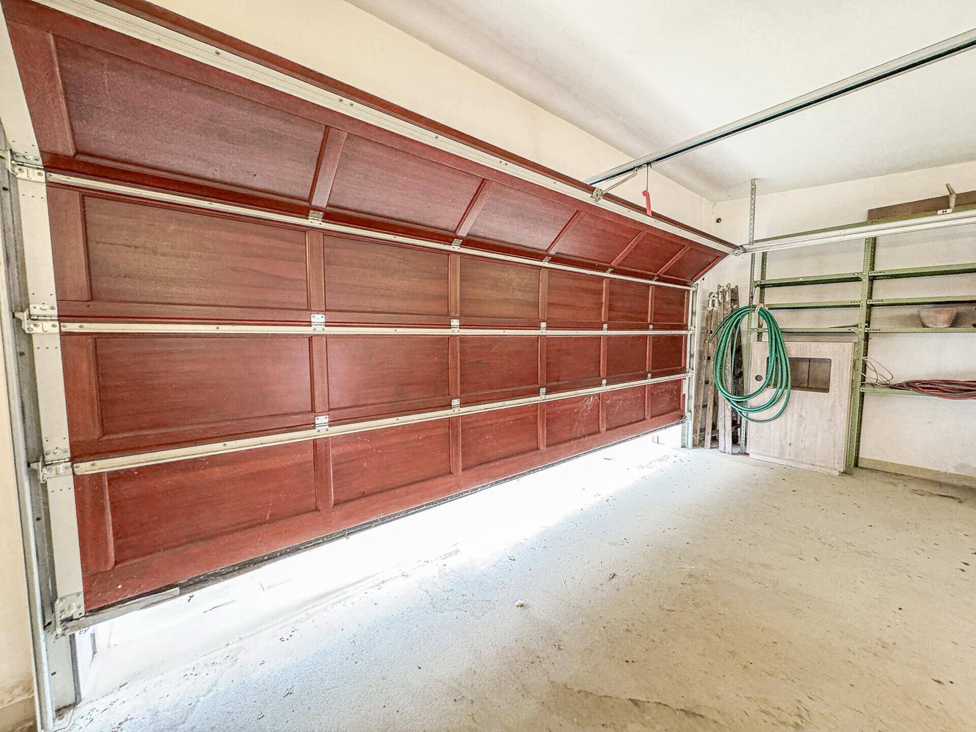Innenansicht einer Garage mit geöffnetem Tor und praktischem Stauraum an den Wänden.