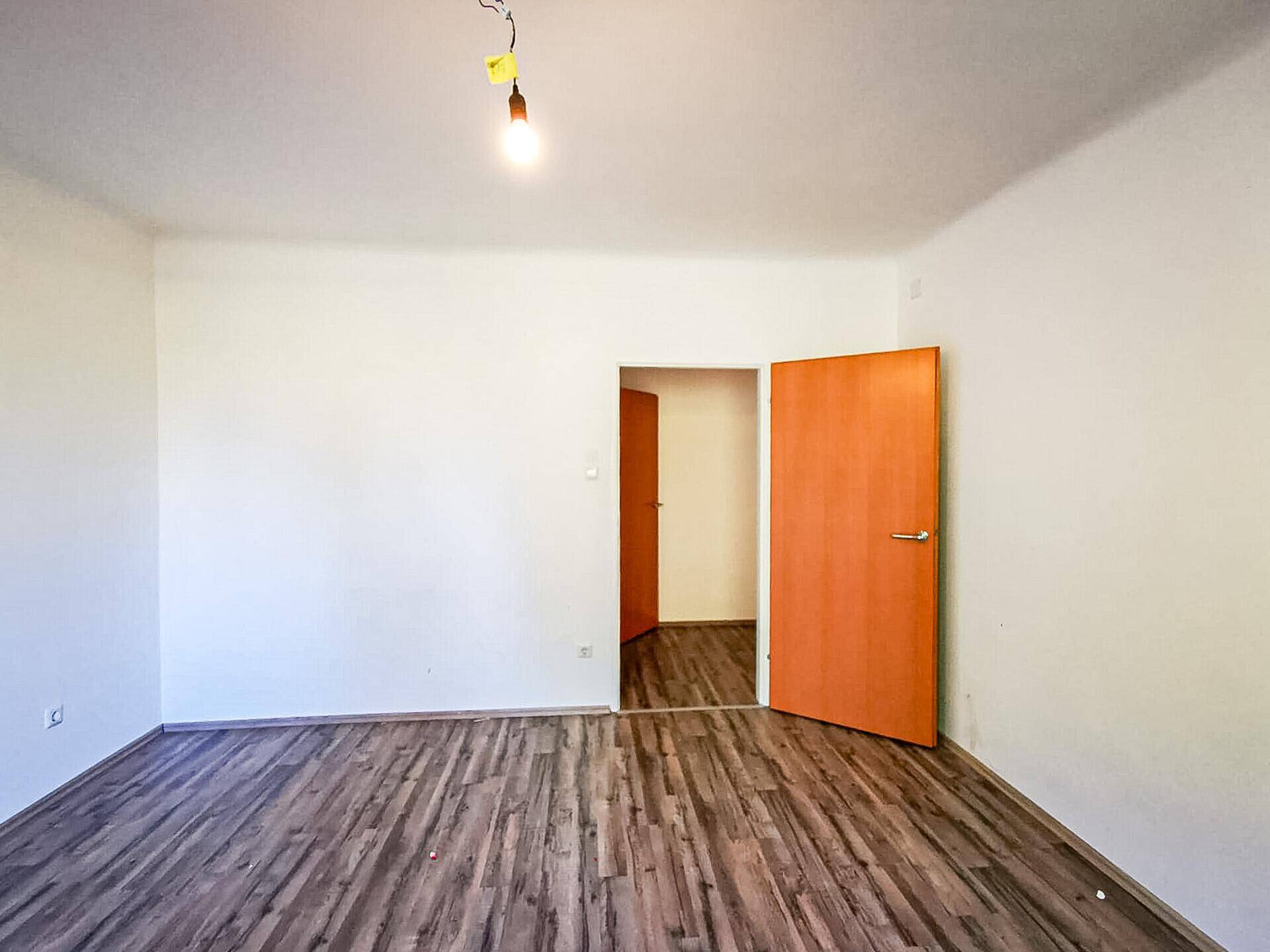 Leerer Raum mit Holzboden und zwei Holztüren, die zu weiteren Zimmern führen.