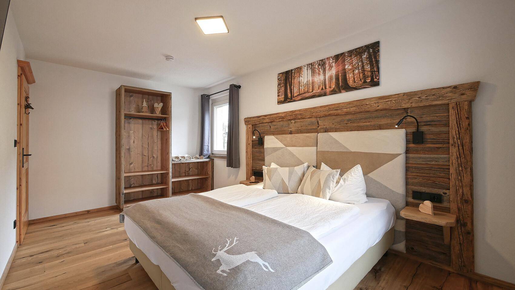 Gemütliches Schlafzimmer mit Holzboden, rustikalem Doppelbett und dekorativem Bild.