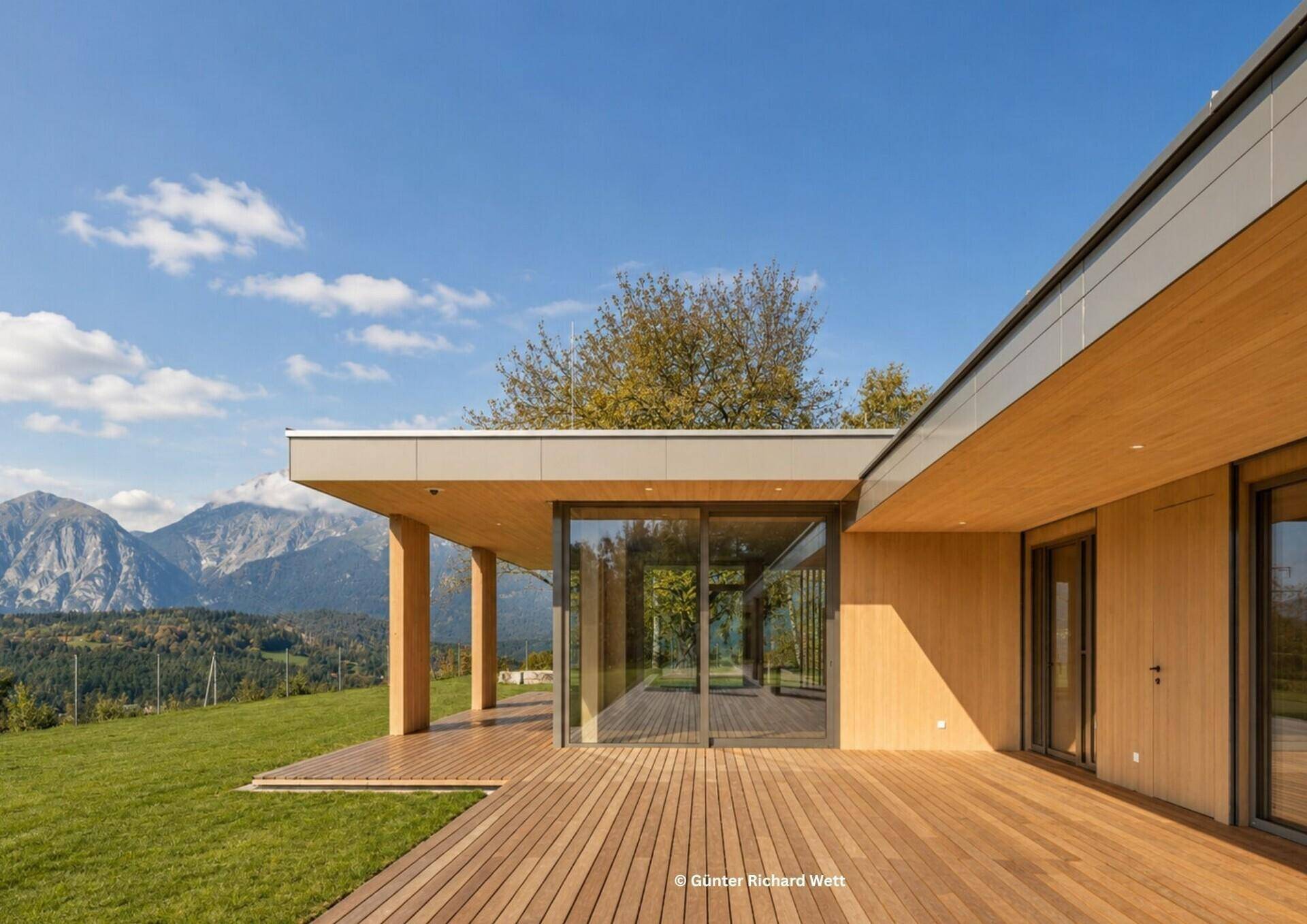 Weitläufige Holzterrasse mit Panoramablick auf die Berge und die grüne Hügellandschaft.