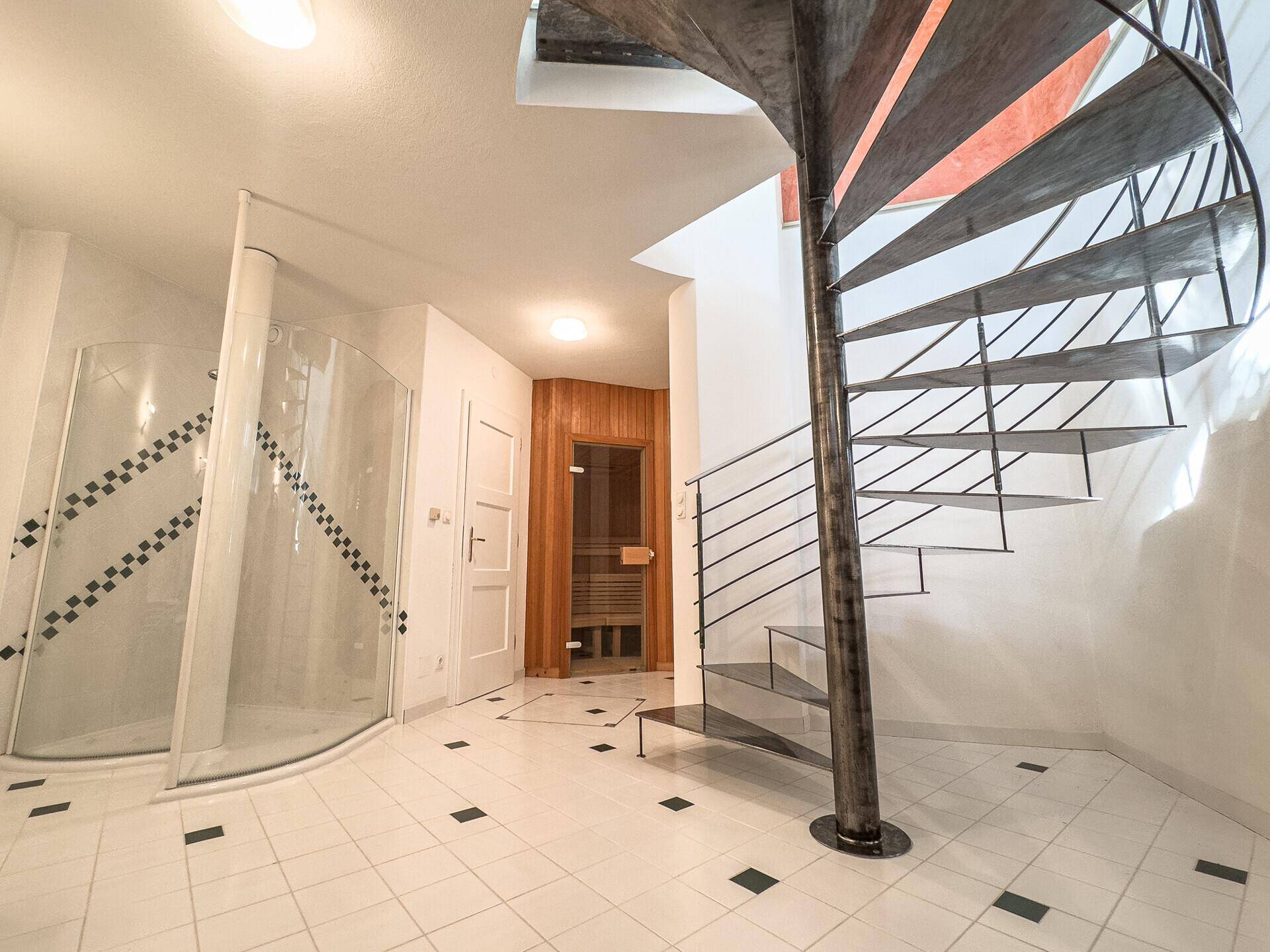 Wellnessbereich mit Dusche, Zugang zur Sauna und eleganter Wendeltreppe.