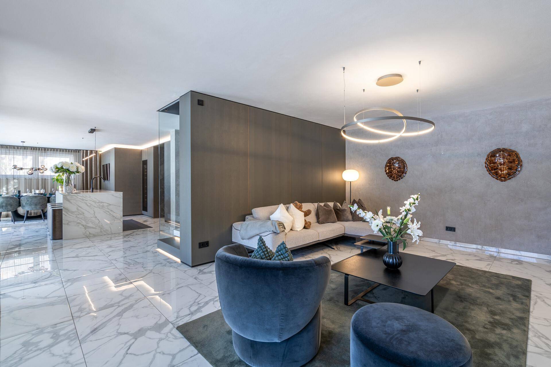 Geräumiges Wohnzimmer mit luxuriösem Marmorboden, modernen Möbeln und indirekter Beleuchtung.