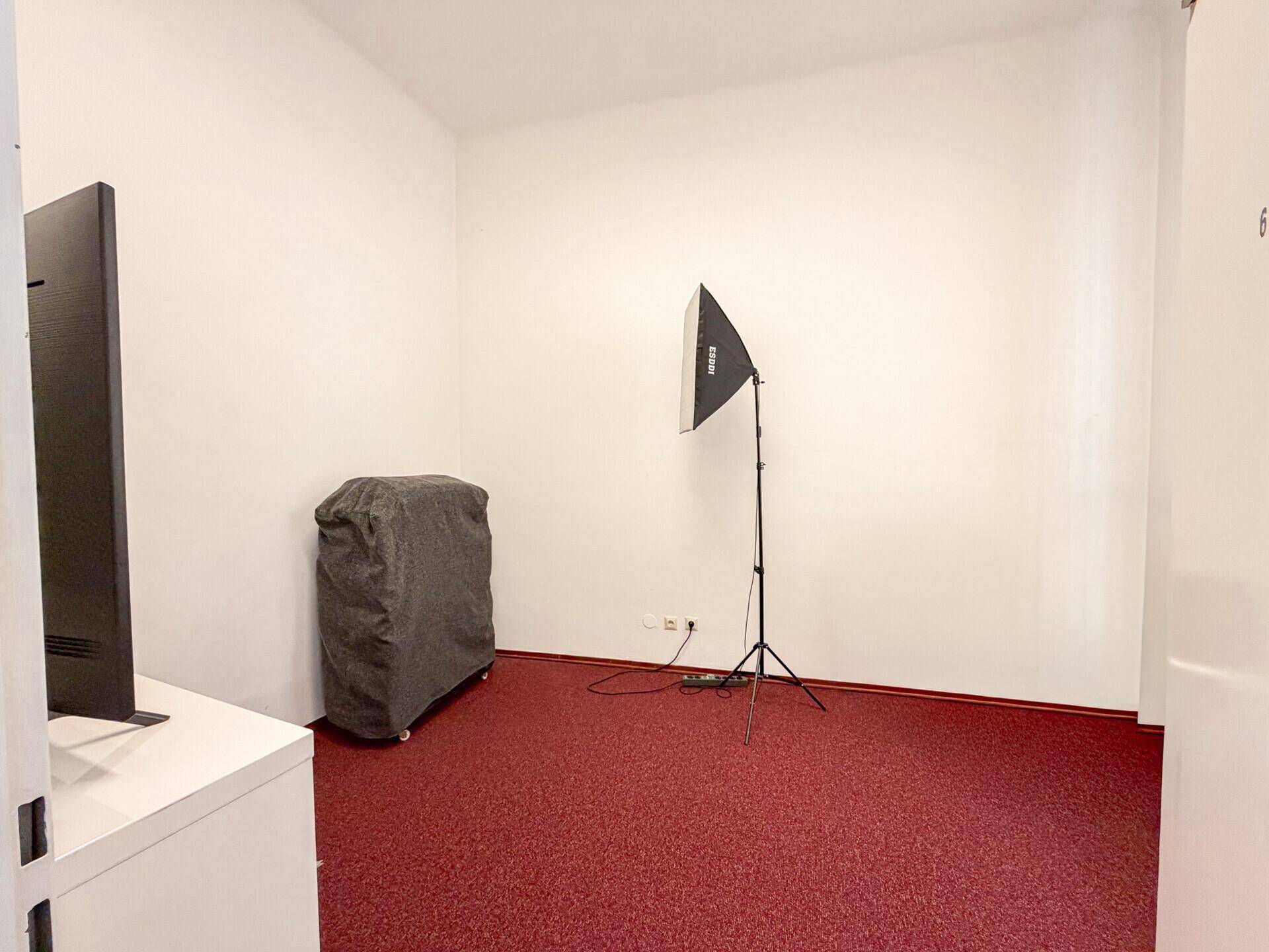 Kleiner Raum mit rotem Teppichboden und professioneller Beleuchtungsausrüstung.