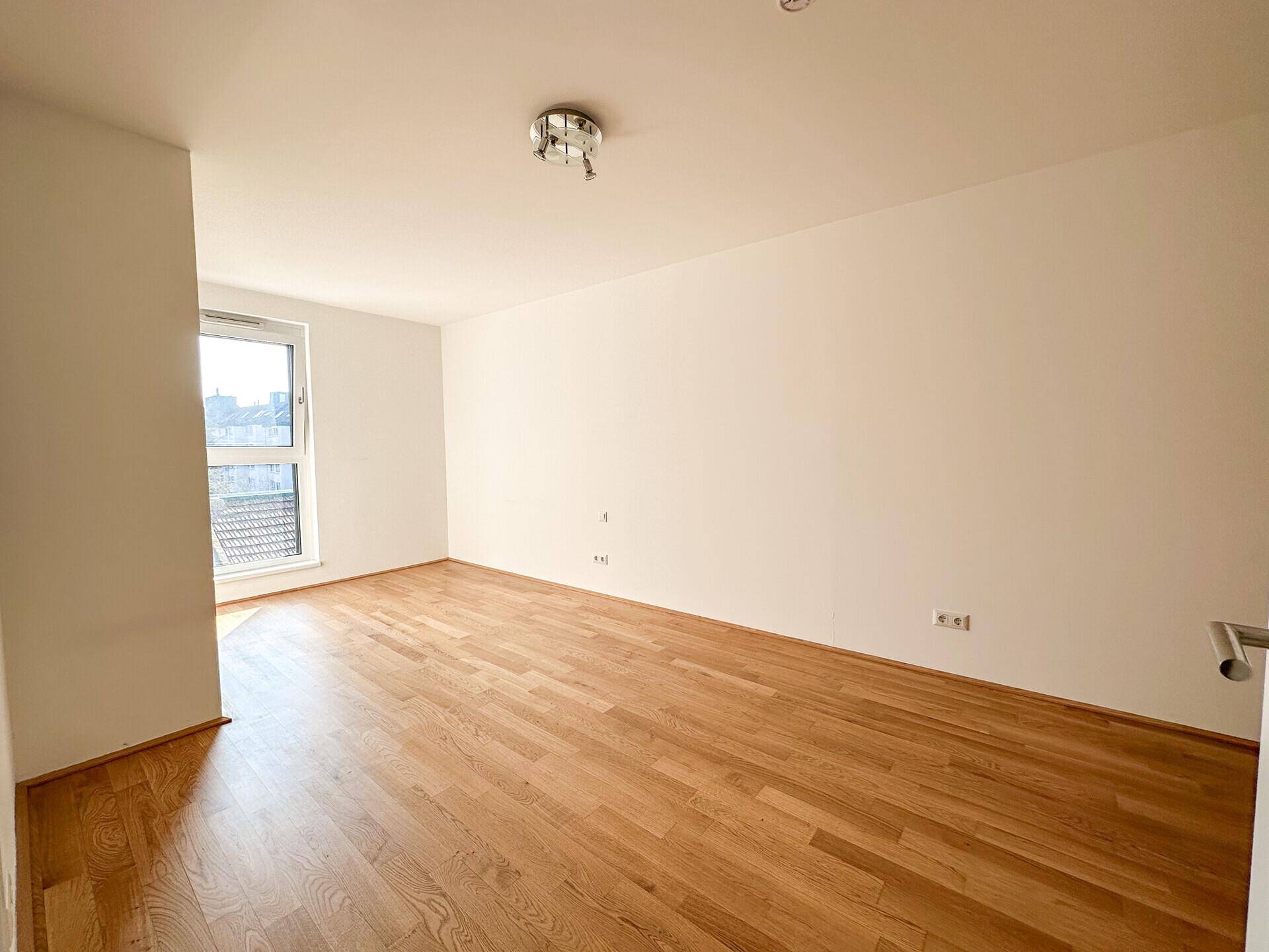 Lichtdurchflutetes Schlafzimmer mit Holzboden und weiß gestrichenen Wänden.