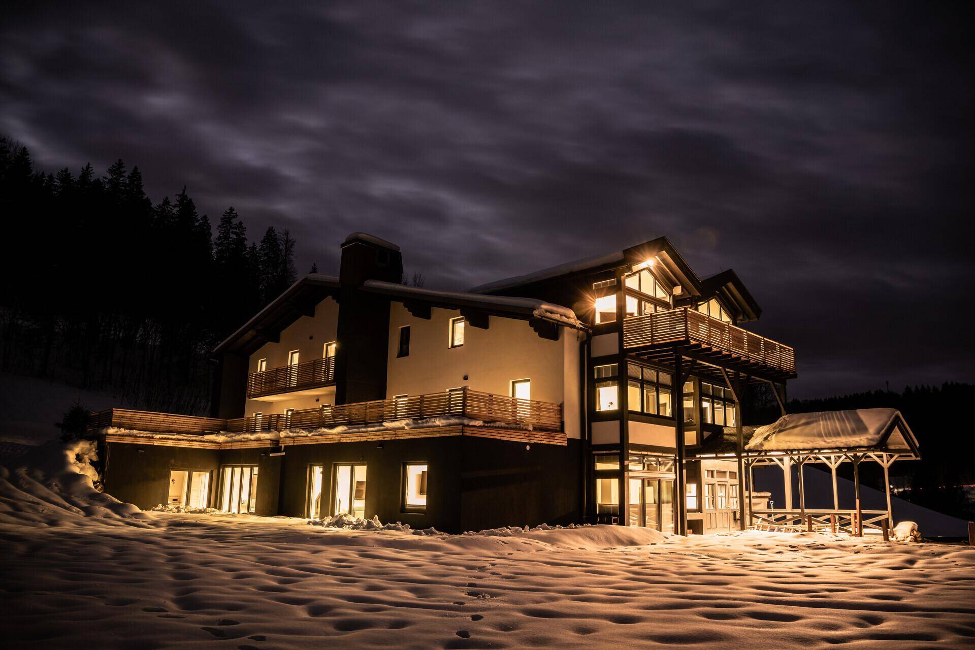 Das moderne Gebäude in winterlicher Nachtbeleuchtung, umgeben von einer Schneelandschaft.