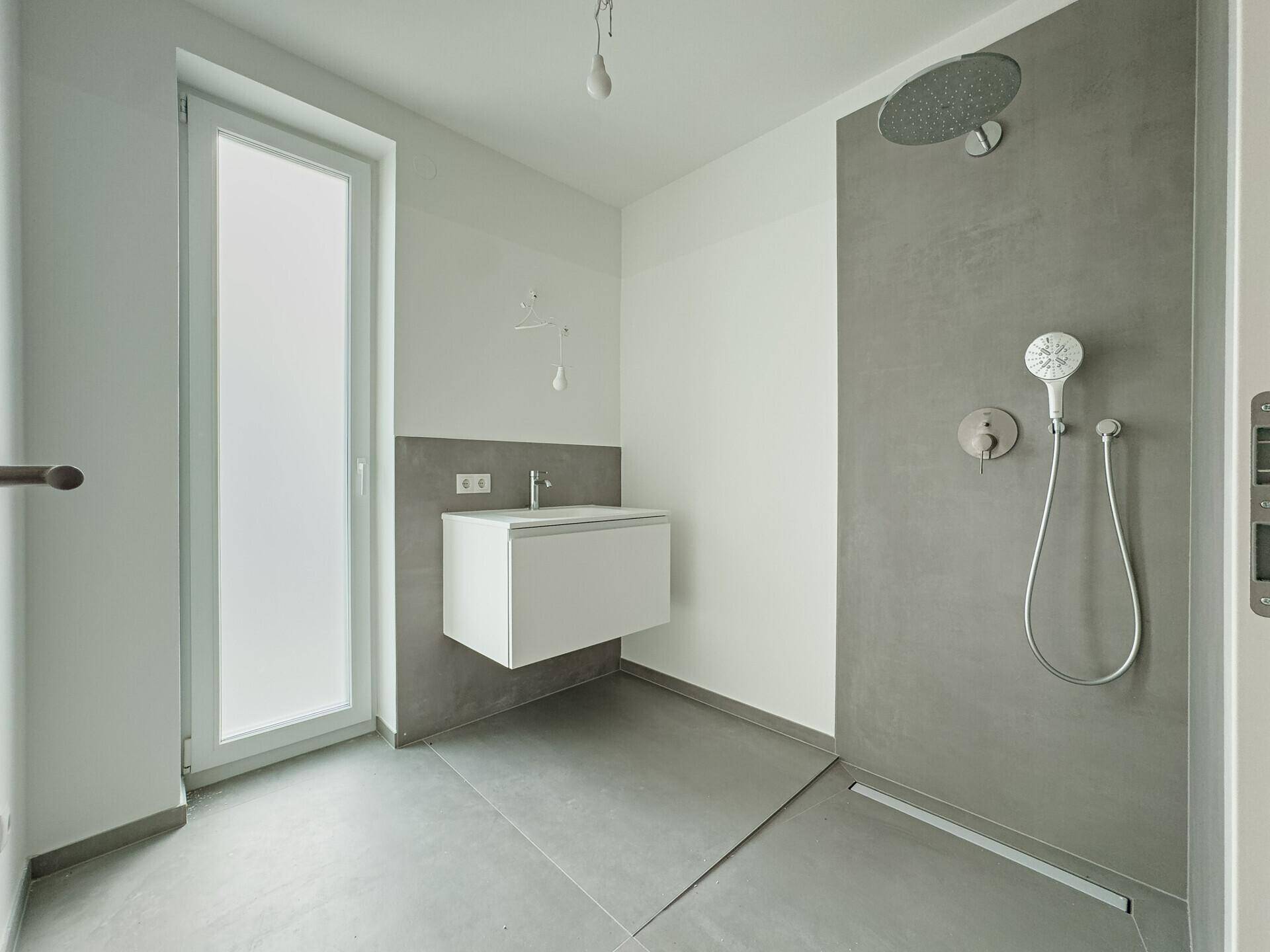 Zeitgemäßes Badezimmer mit ebenerdiger Dusche, modernem Waschbecken und großem Fenster.