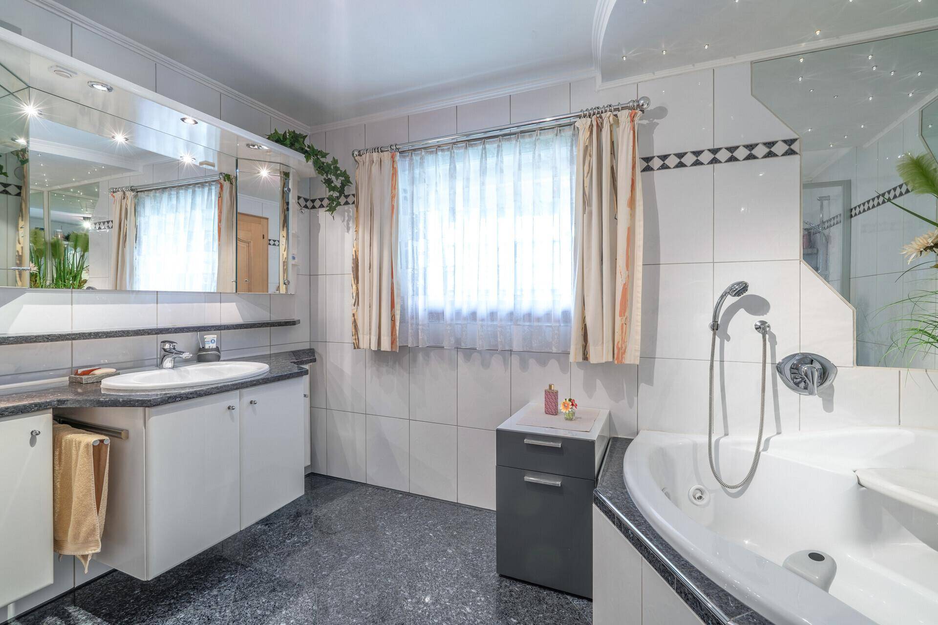 Modernes Badezimmer mit Whirlpool-Badewanne, Doppelwaschbecken und großem Spiegelschrank.