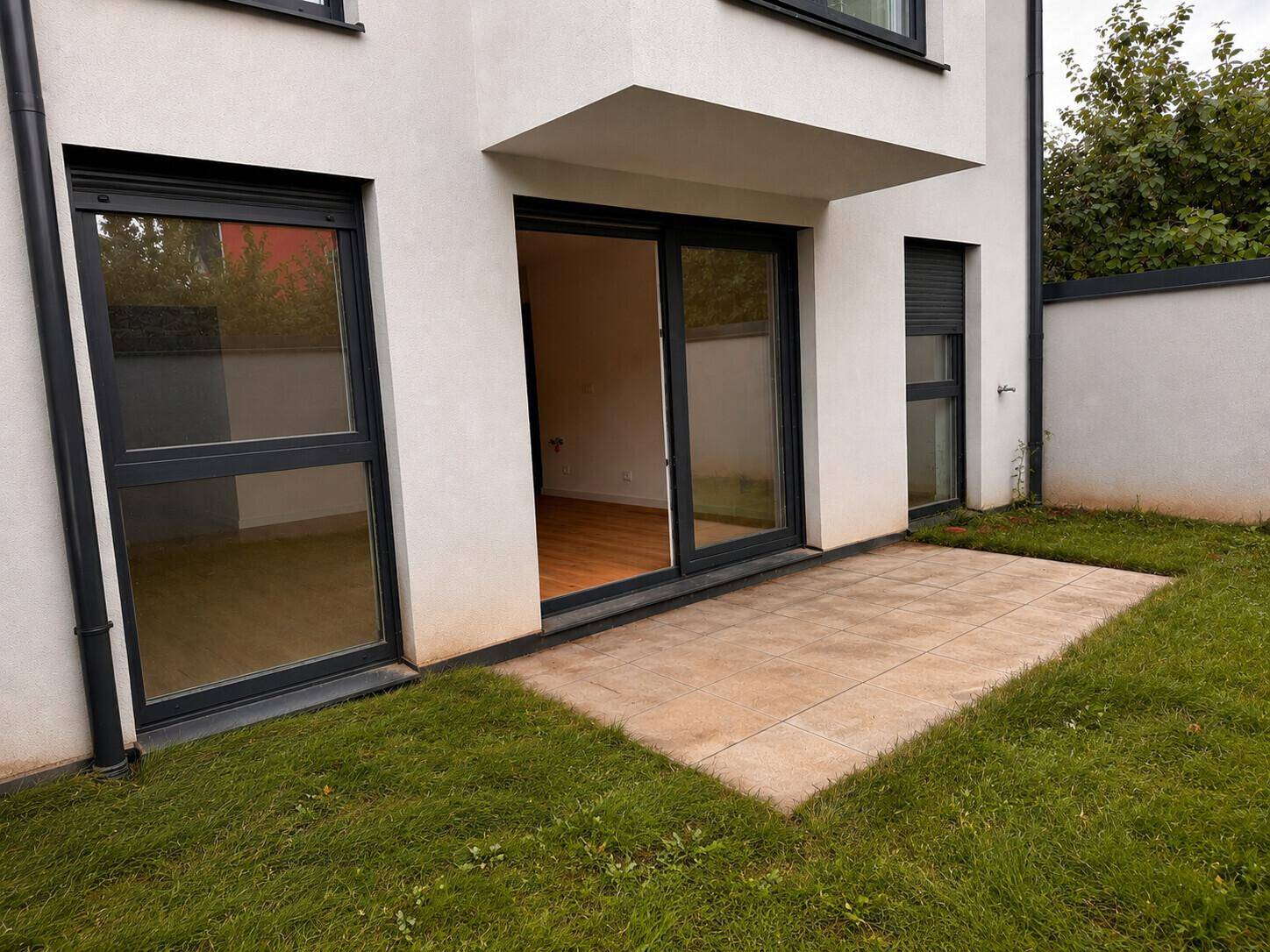 Gemütliche Terrasse mit Steinplatten und angrenzendem Rasenbereich, ideal für entspannte Stunden im Freien.