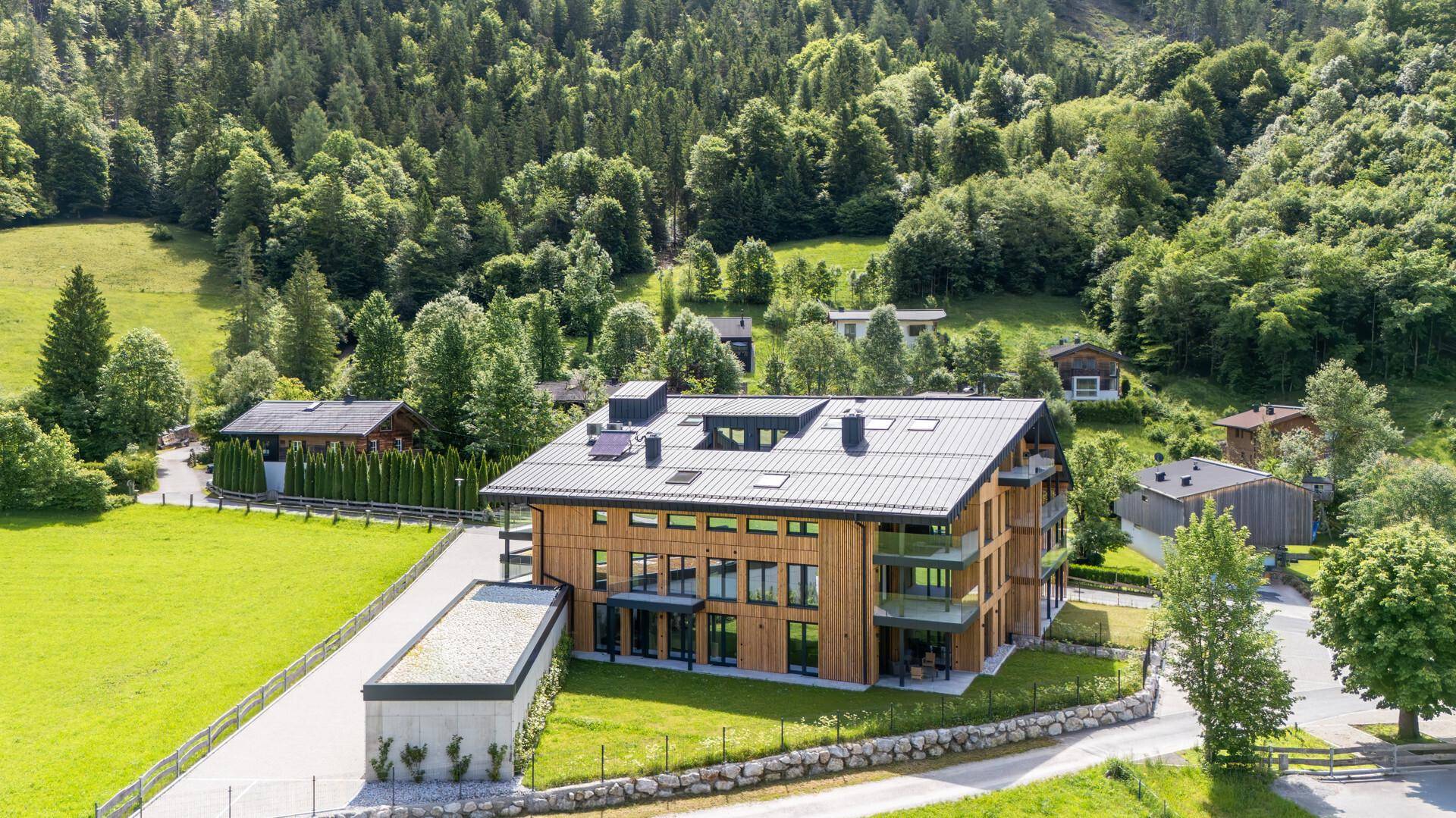 Neues Apartmentgebäude in grüner Umgebung mit Zufahrt und separatem Garagengebäude.