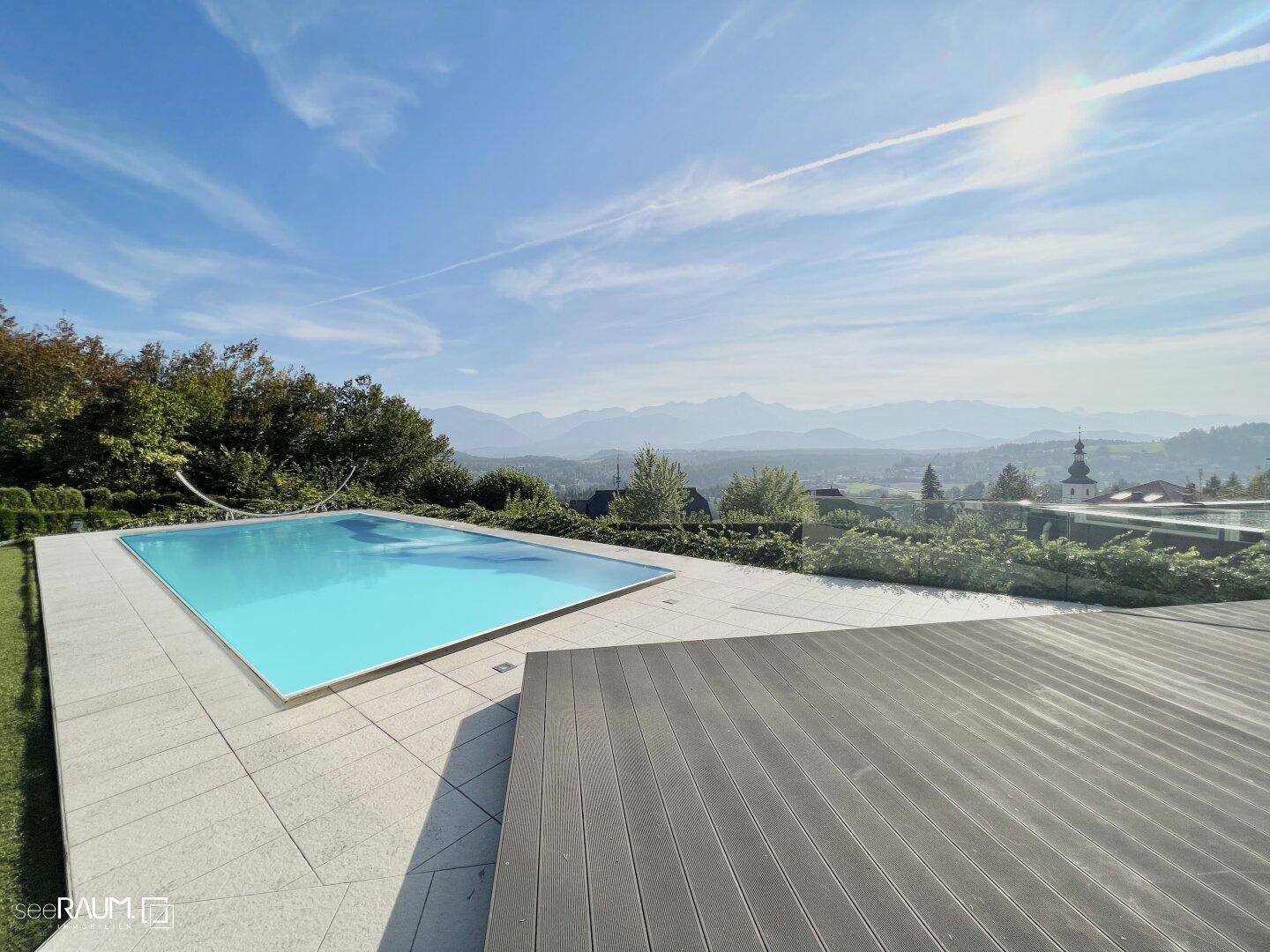 Exklusiver Außenbereich mit Infinity-Pool, Holzdeck und atemberaubendem Blick auf die umliegende Berglandschaft.