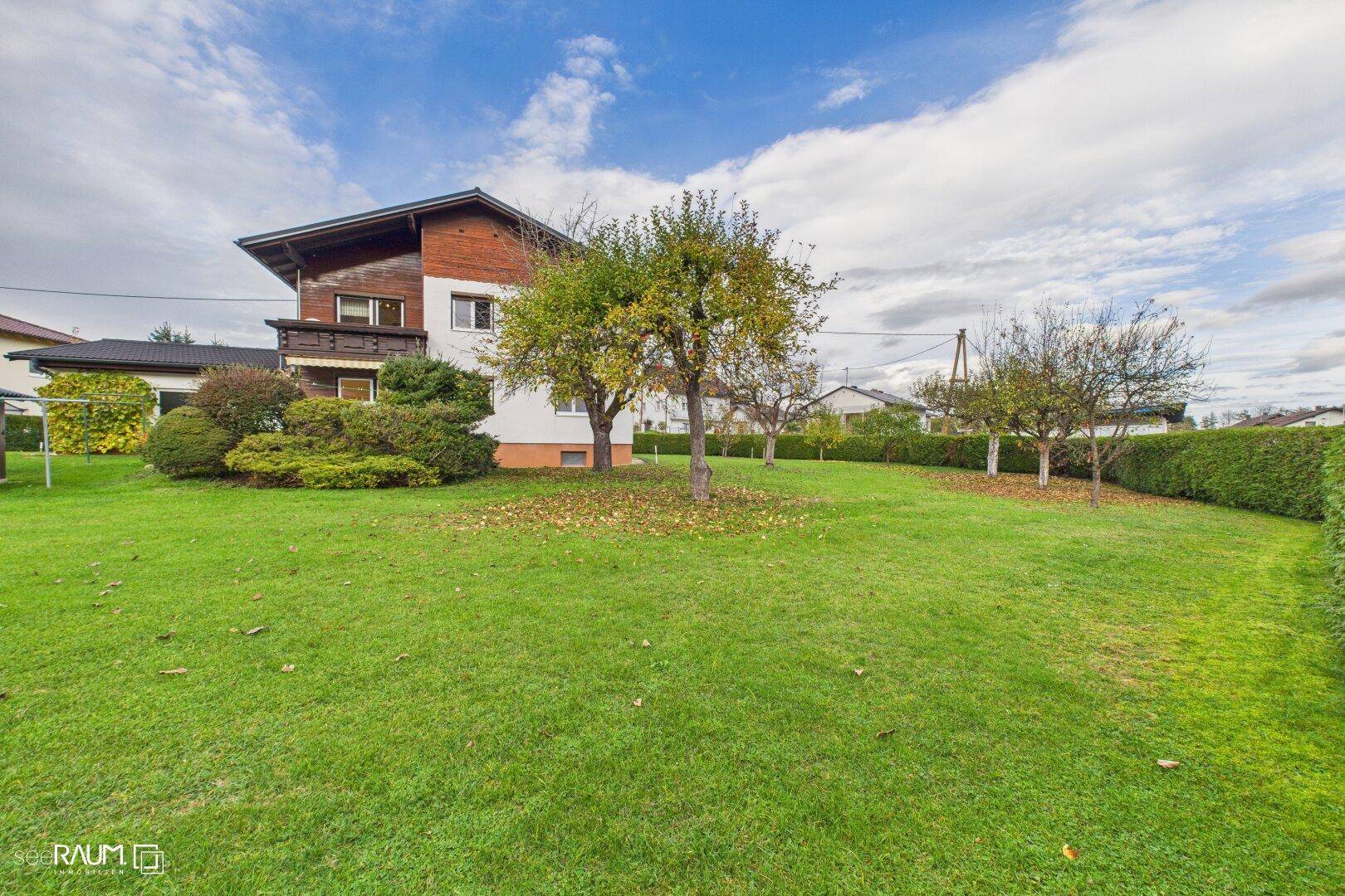 Weitläufiger Gartenbereich mit Rasenfläche, Obstbäumen und Blick auf die Hausfassade.