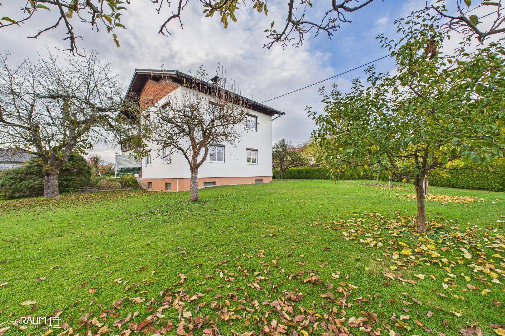 Gepflegter Garten mit Rasen, Obstbäumen und herbstlichem Laub rund um das Einfamilienhaus.
