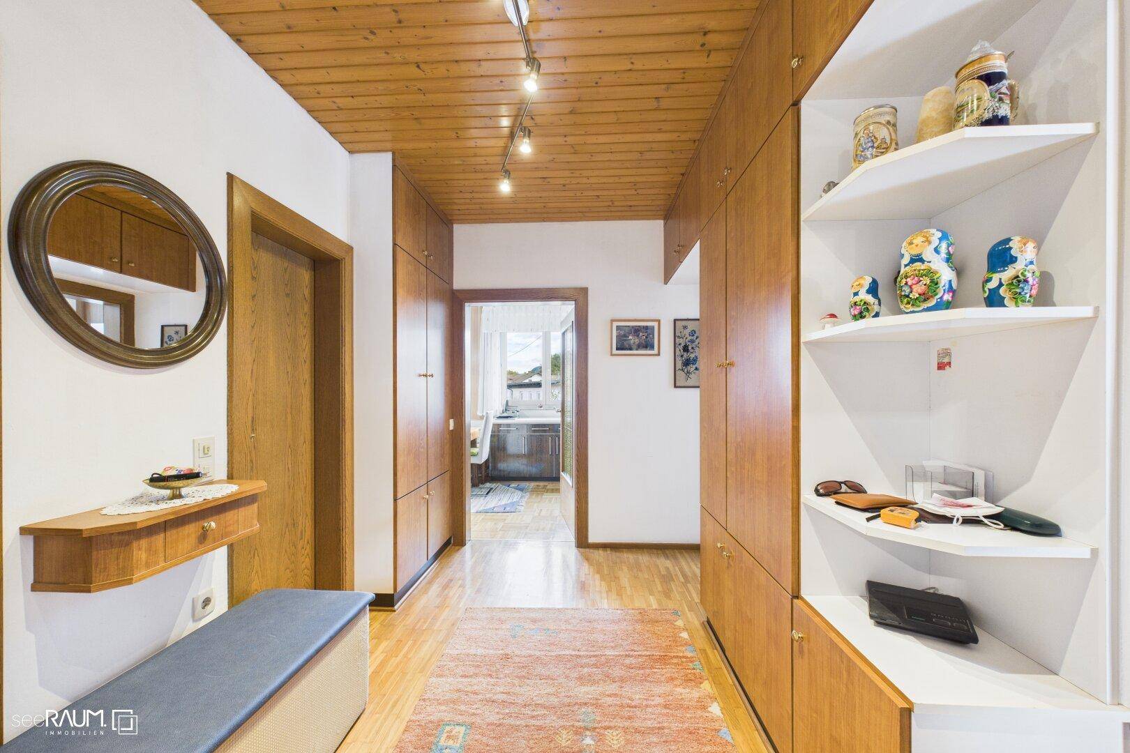 Gemütlicher Flur mit Holzdecken, Einbauschränken und einem runden Spiegel als Dekoration.