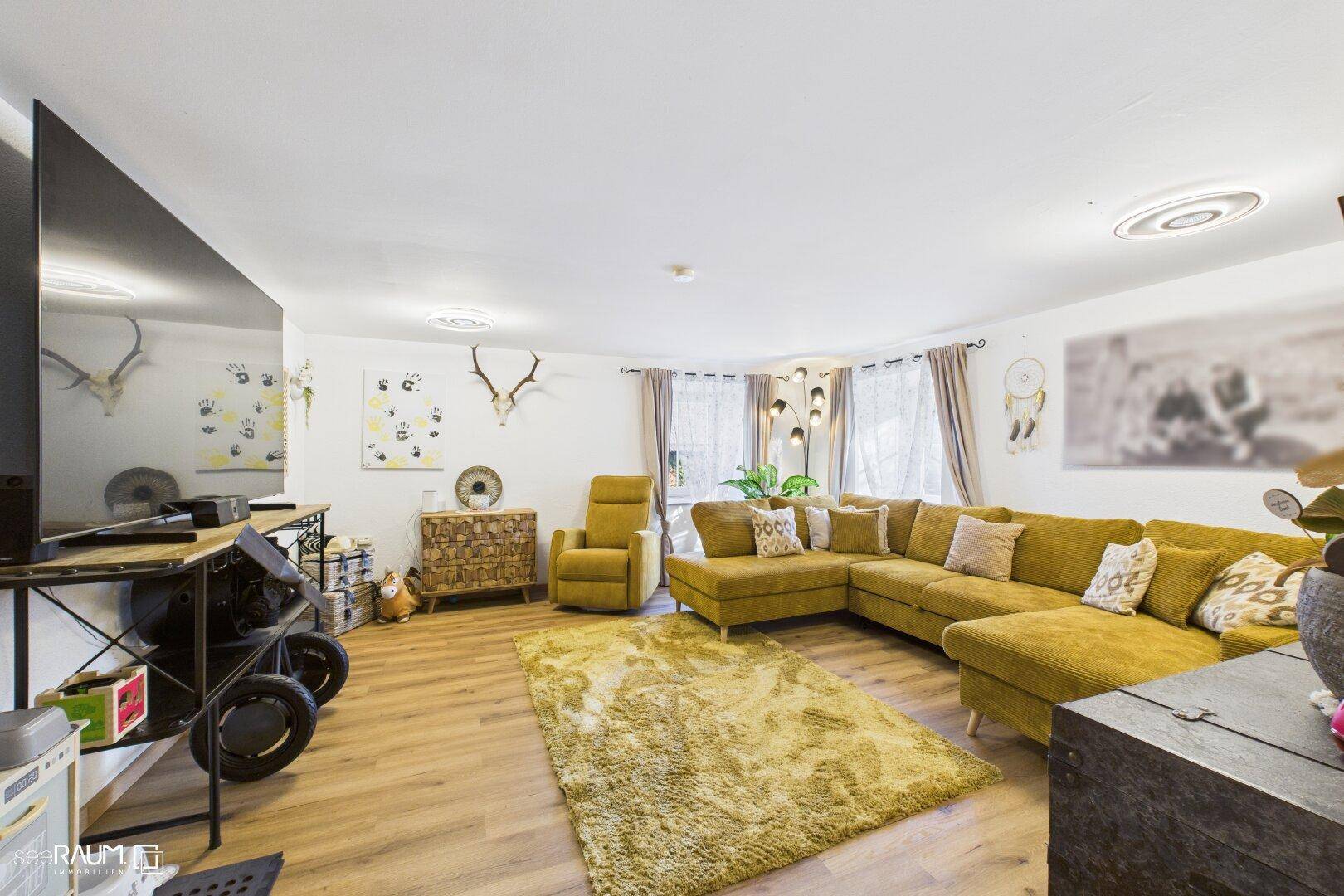 Geräumiges Wohnzimmer mit gelbem Ecksofa, Holzboden und alpinen Dekorationselementen.