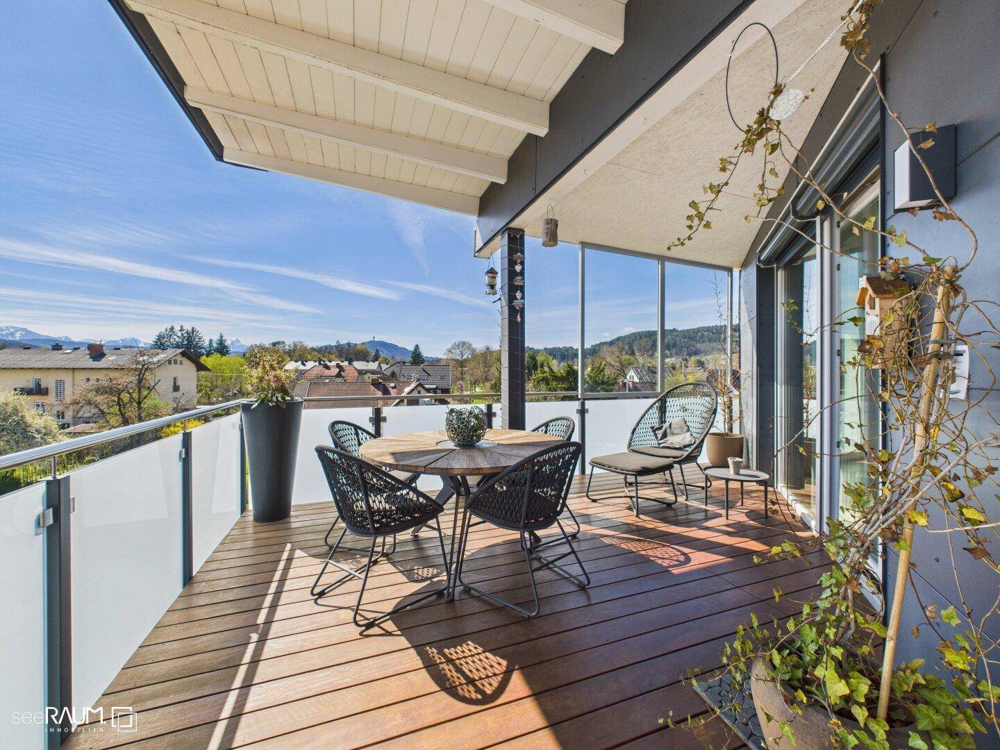 Helle Terrasse mit Esstisch, modernen Möbeln und Panoramablick auf die Stadt und die Berge.