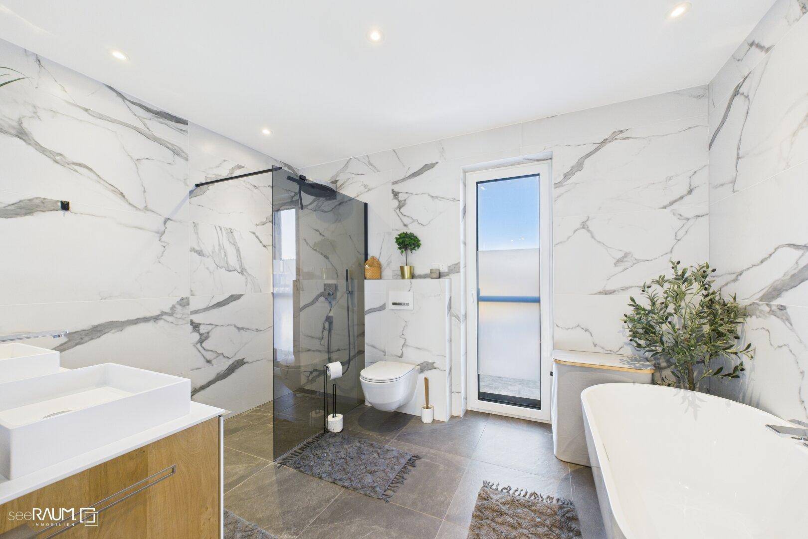Luxuriöses Badezimmer mit Marmorfliesen, begehbarer Dusche und freistehender Badewanne.