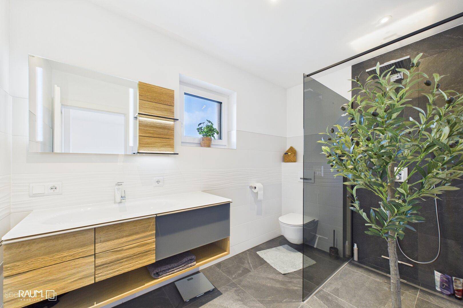Modernes Badezimmer mit Holzwaschtisch, Spiegel, ebenerdiger Dusche und Fenster.