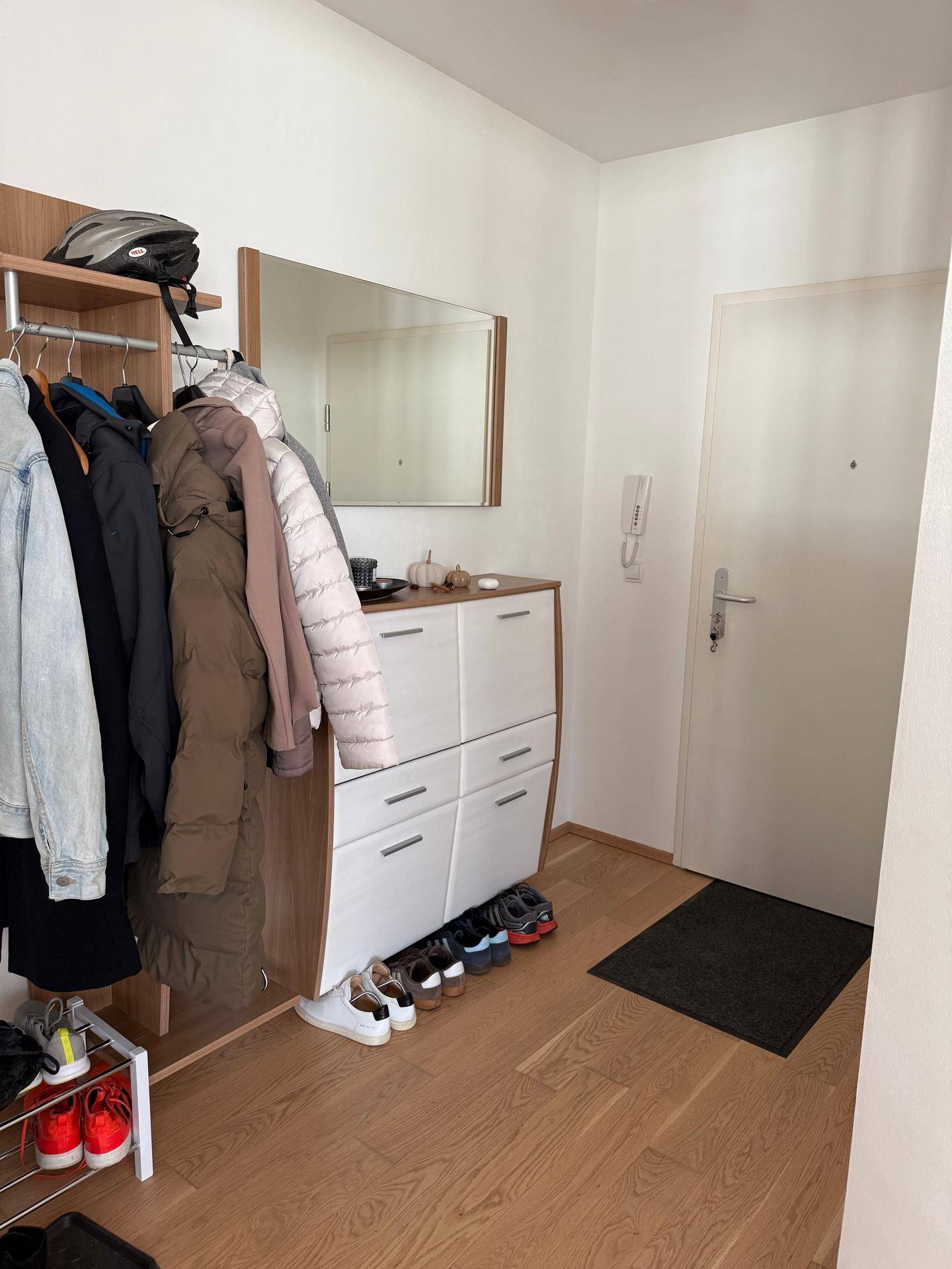 Heller Eingangsbereich mit Garderobe, Schuhschrank und der Eingangstür zur Wohnung.
