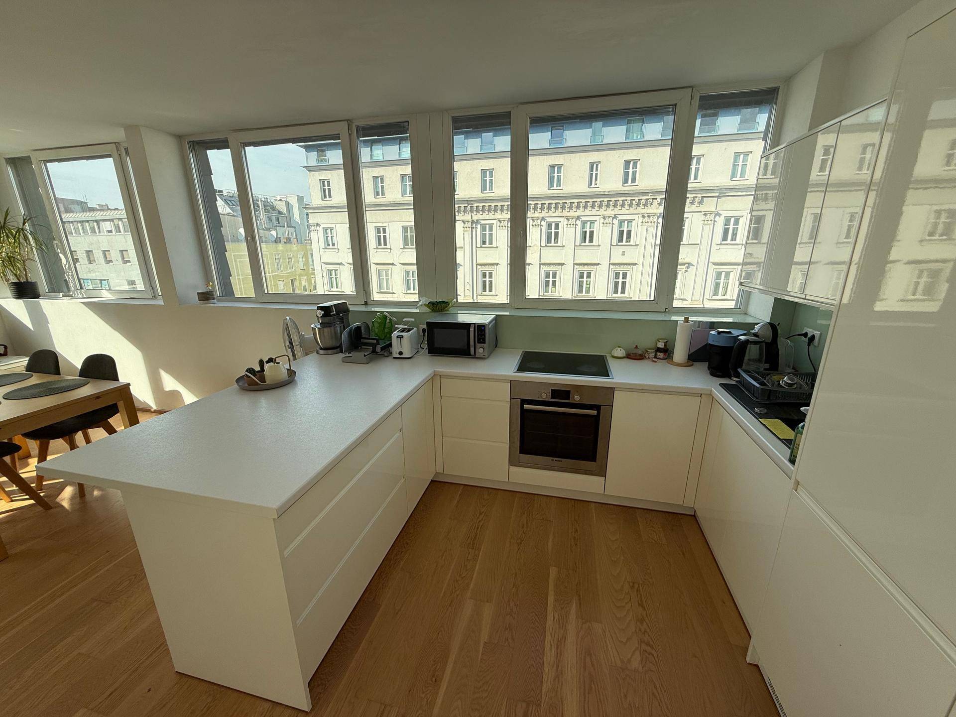Moderne Küche mit weißer Kücheninsel, integrierten Geräten und weitem Stadtblick.