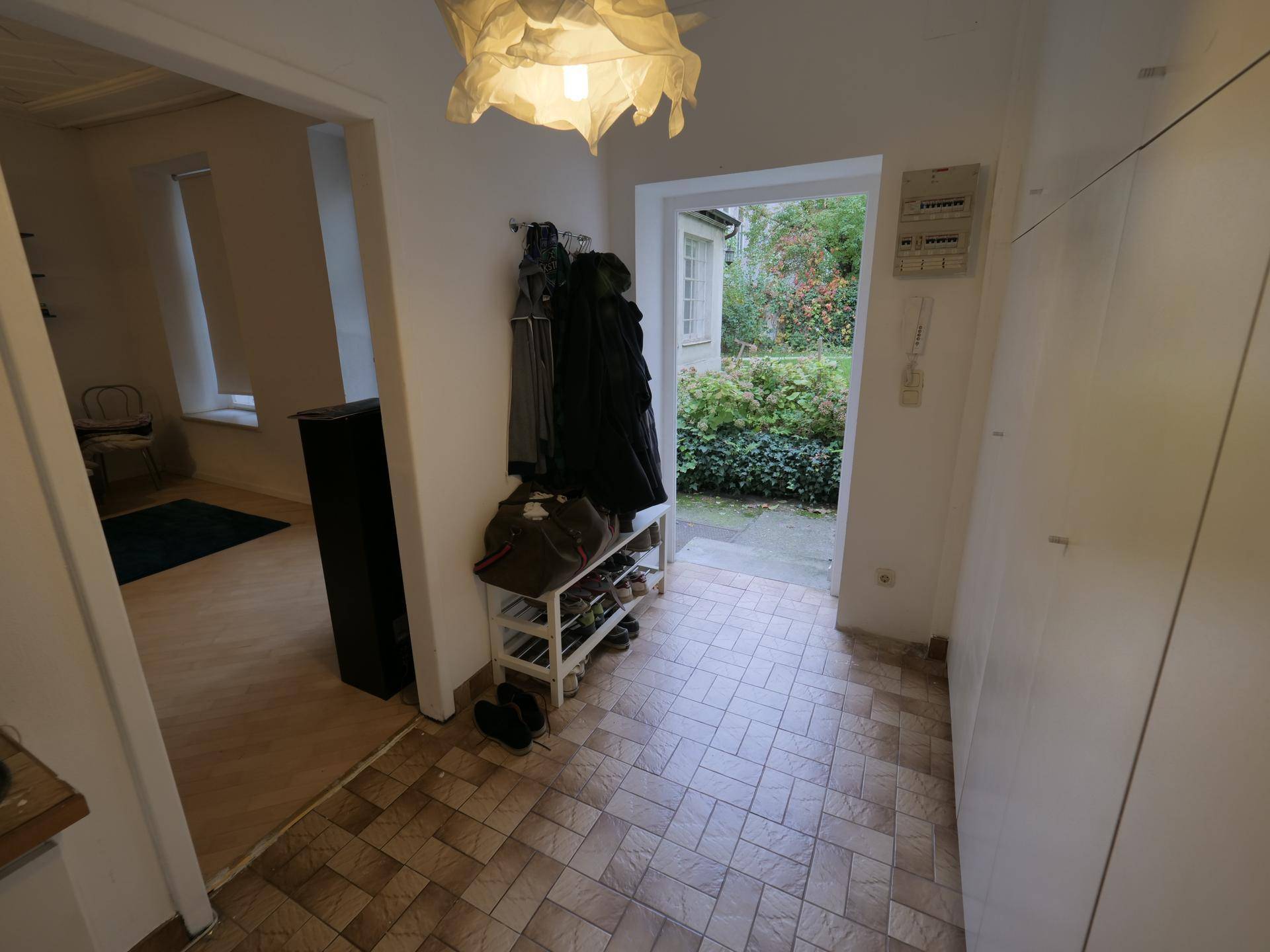 Eingangsbereich mit Fliesenboden, Garderobe und direktem Zugang zum begrünten Garten.