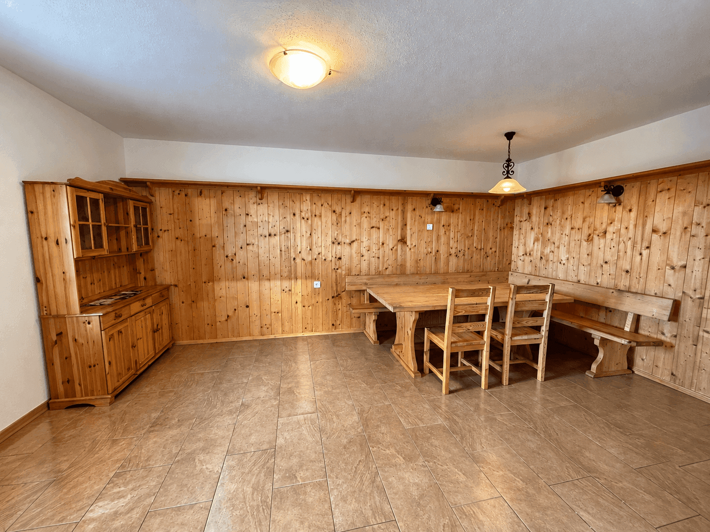 Rustikaler Essbereich mit Holzvertäfelung, großem Holztisch und passenden Bänken.