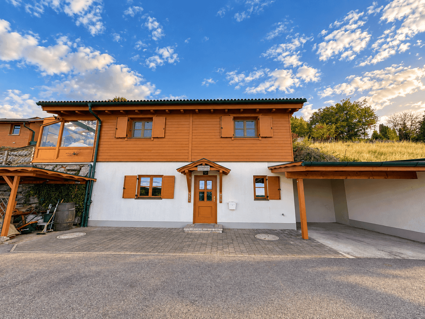 Charmantes Holzhaus mit weißer Fassade, Holzfensterläden und Carport.