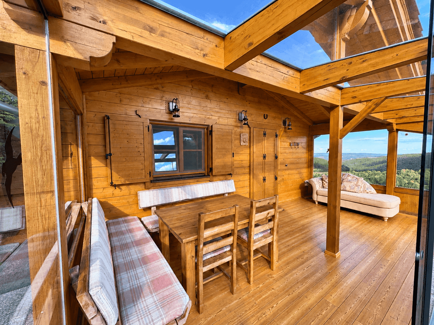 Heller Wintergarten mit Holzkonstruktion, Glasdach und Sitzgelegenheiten mit Panoramablick.