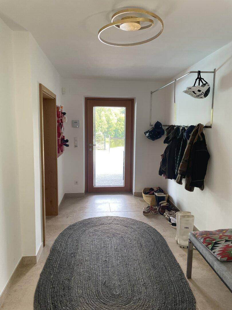 Heller Eingangsbereich mit Fliesenboden, Garderobe und einer modernen Deckenleuchte.