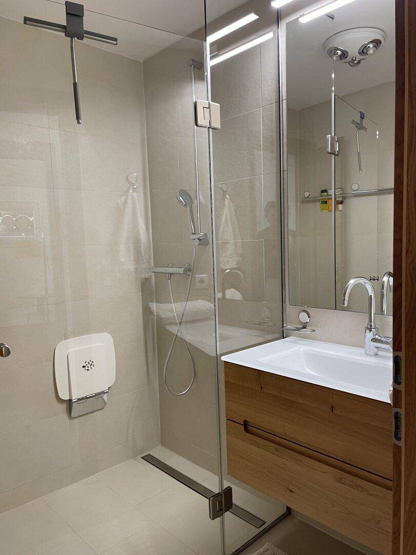 Modernes Badezimmer mit begehbarer Dusche, Einzelwaschbecken und hellen Fliesen, ausgestattet für Komfort.
