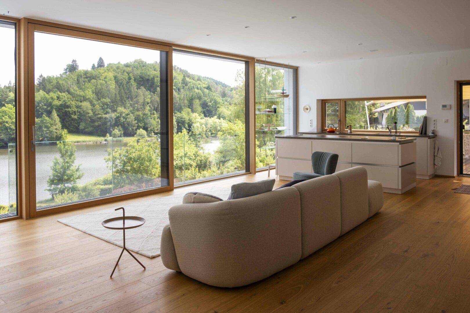 Geräumiger Wohnbereich mit offener Küche, bequemer Couch und Panoramafenstern mit Seeblick.