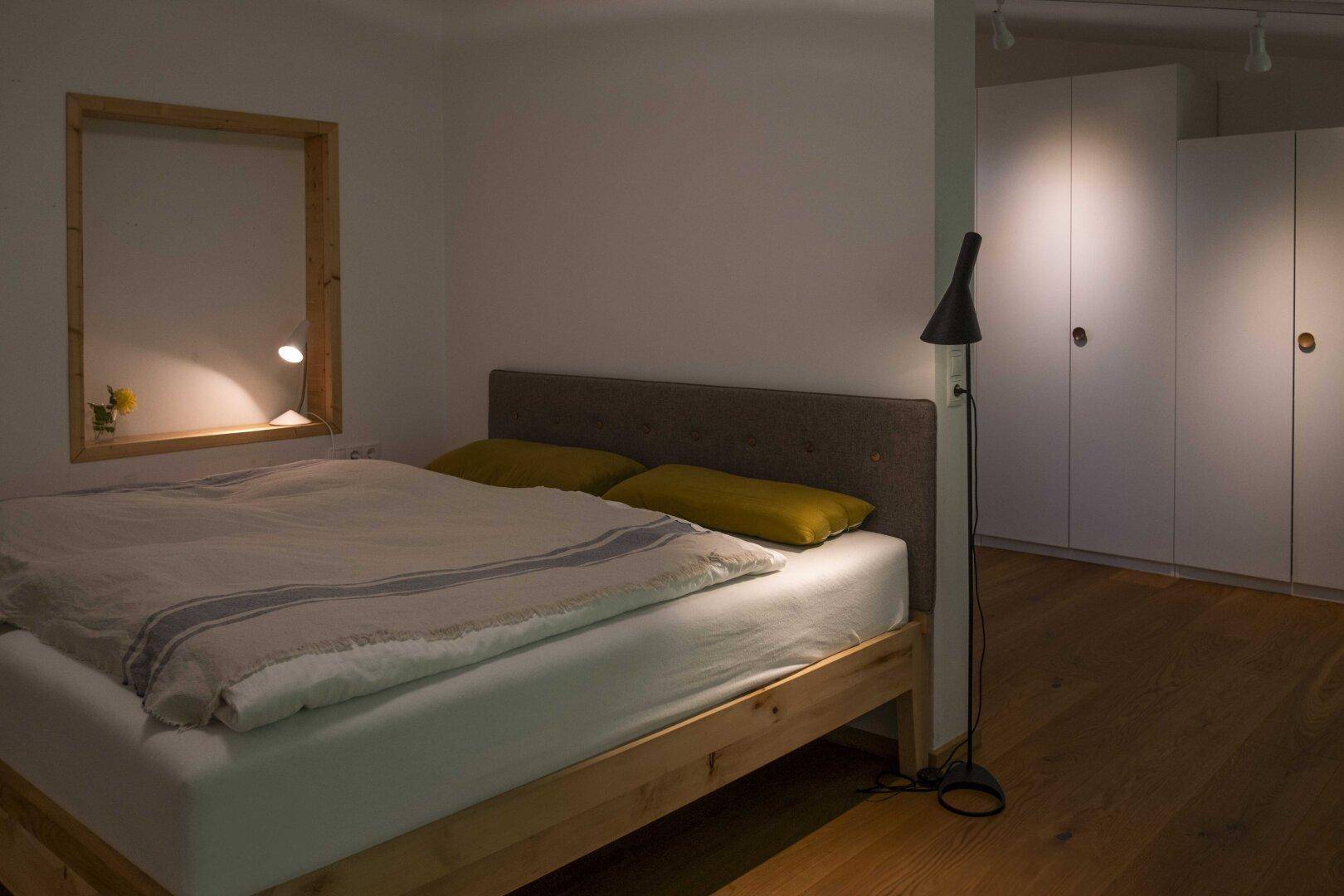 Gemütliches Schlafzimmer mit Holzbett, Einbauschränken und indirekter Beleuchtung für eine entspannte Atmosphäre.