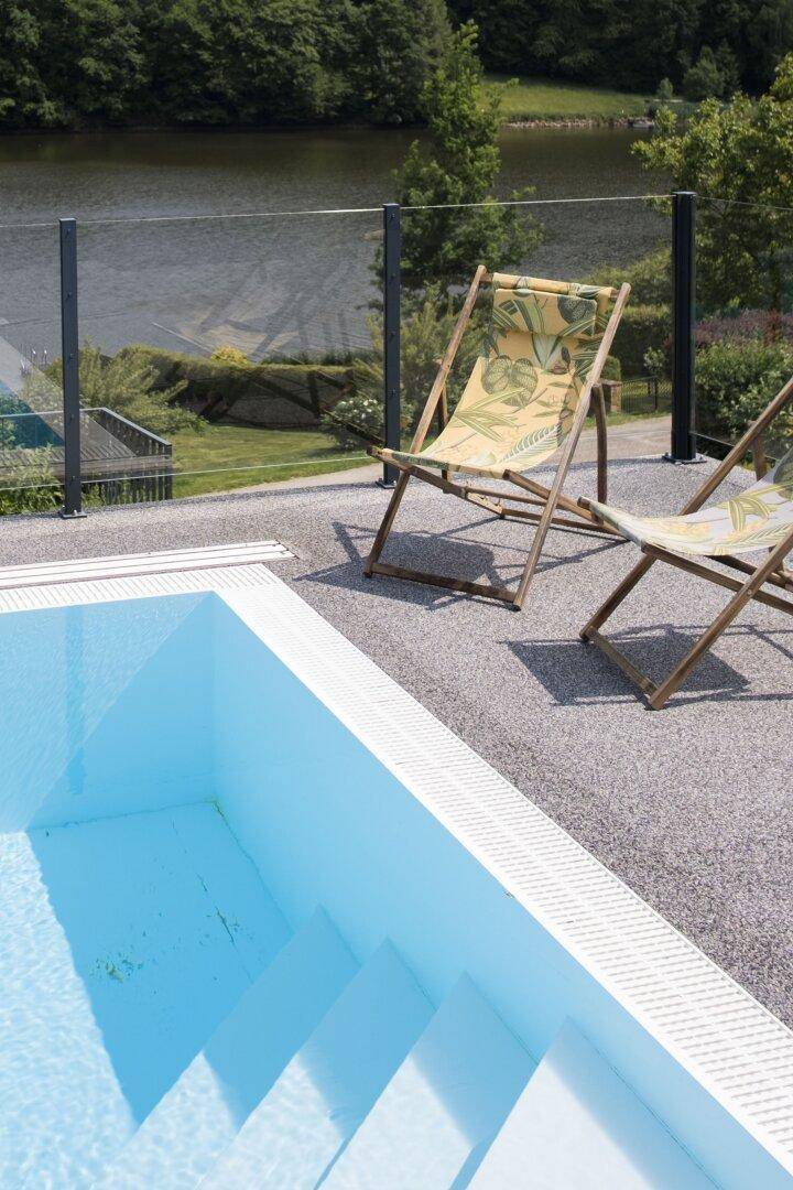 Außenpoolbereich mit Liegestühlen und Blick auf den See, ideal zum Entspannen an sonnigen Tagen.