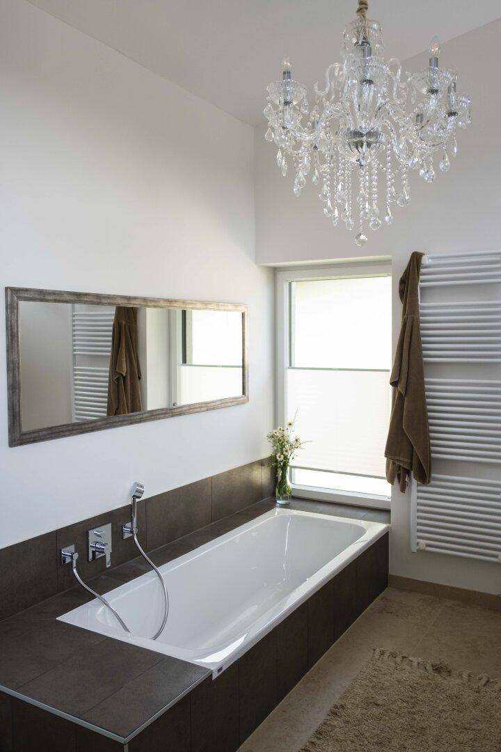 Elegantes Badezimmer mit Badewanne, beheiztem Handtuchhalter und einem Kronleuchter für luxuriöses Ambiente.