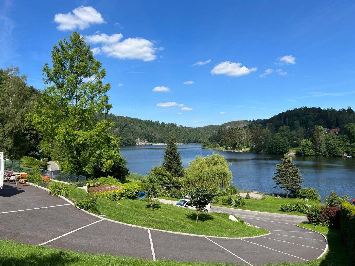Panoramablick auf den See mit umliegender Natur und Parkplätzen, ideal für Erholungssuchende.