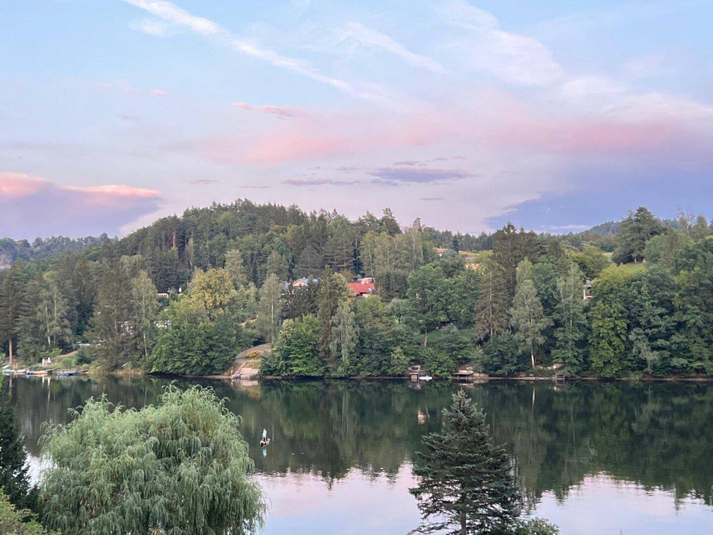 Malerischer See umgeben von Wäldern im sanften Abendlicht, eine ruhige und entspannende Atmosphäre.