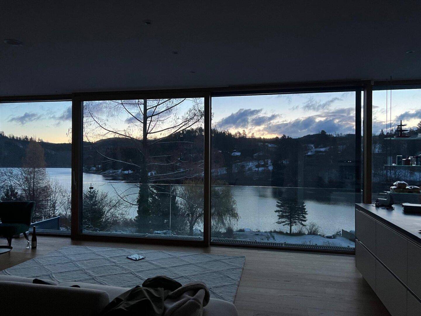 Abendlicher Blick aus dem Wohnzimmer auf den See und die verschneite Winterlandschaft.