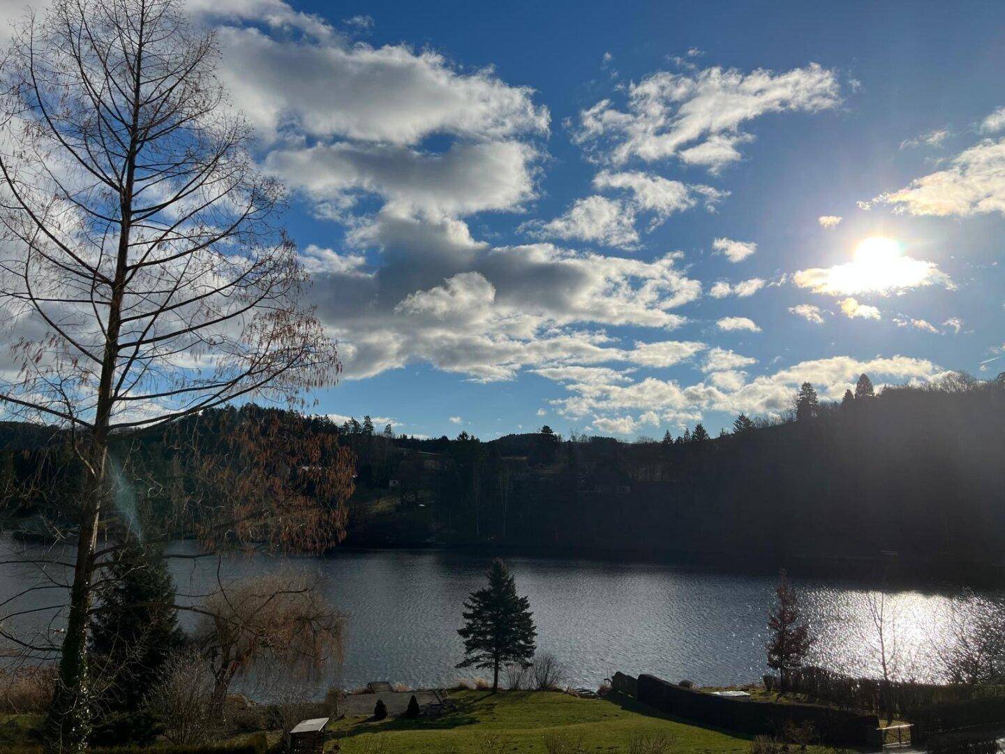 Sonniger Tag am See mit blauem Himmel und Wolken über der Landschaft, eine einladende Aussicht.