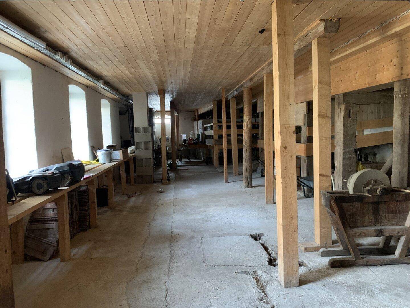 Großer, offener Raum mit Holzbalken, Betonboden und Werkstattcharakter.