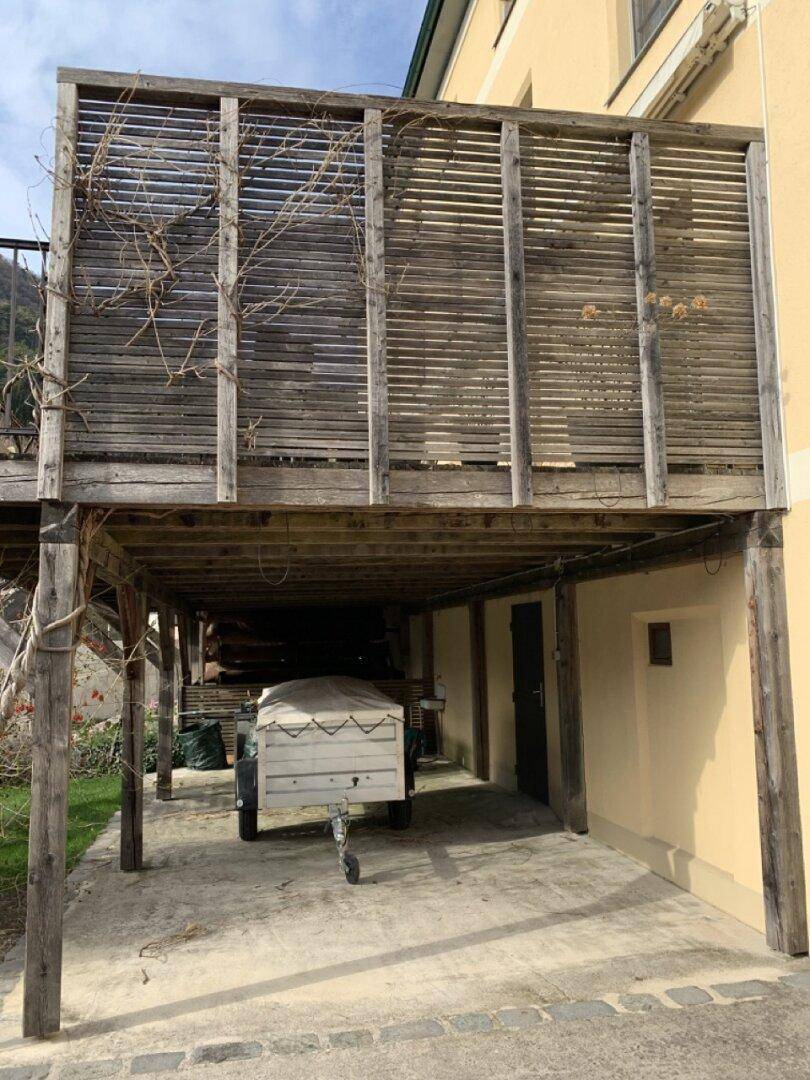 Holzkonstruktion unter einer Terrasse, die als Unterstand oder Parkplatz dient.