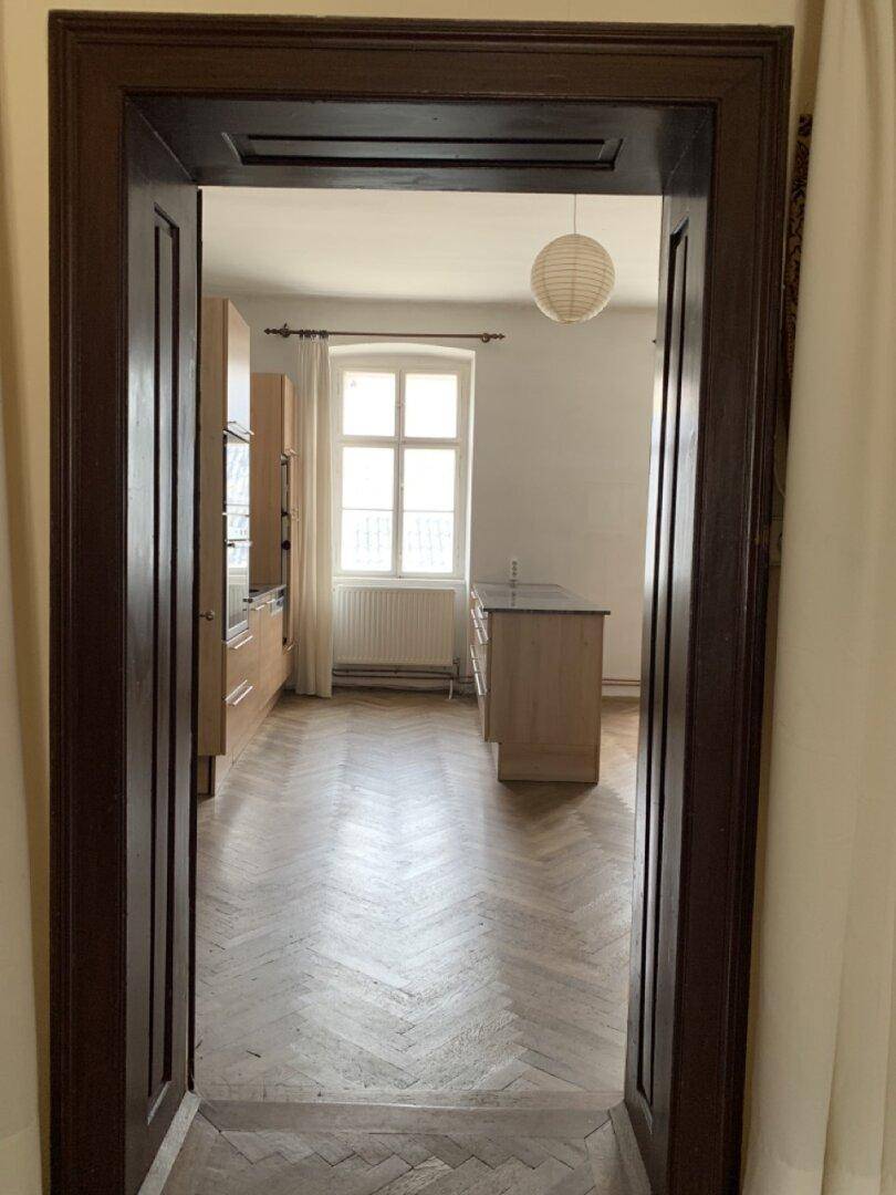 Blick durch eine Tür in eine moderne Küche mit Holzfronten und Parkettboden.