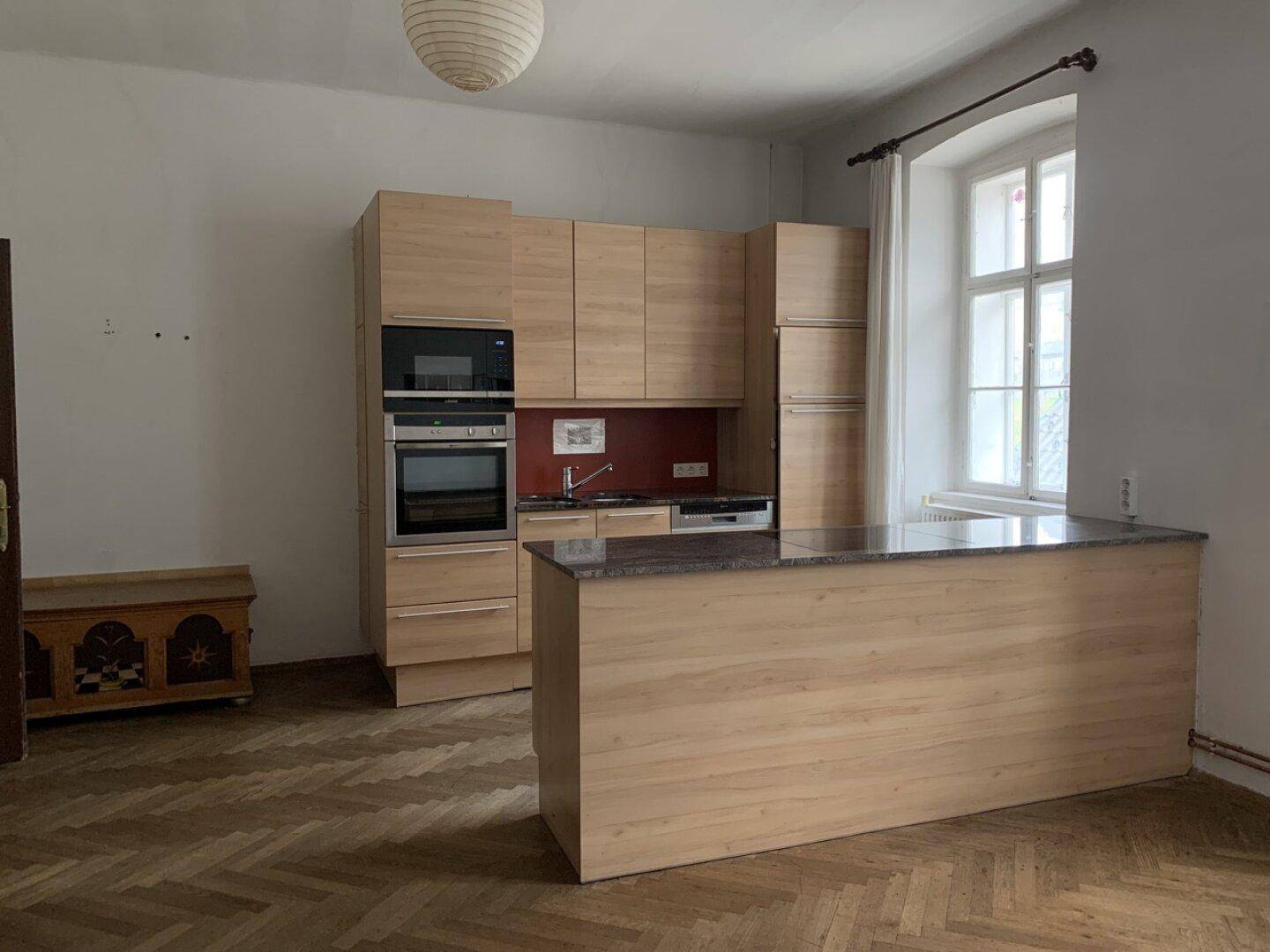 Moderne Einbauküche mit Holzfronten, Kücheninsel und Parkettboden.