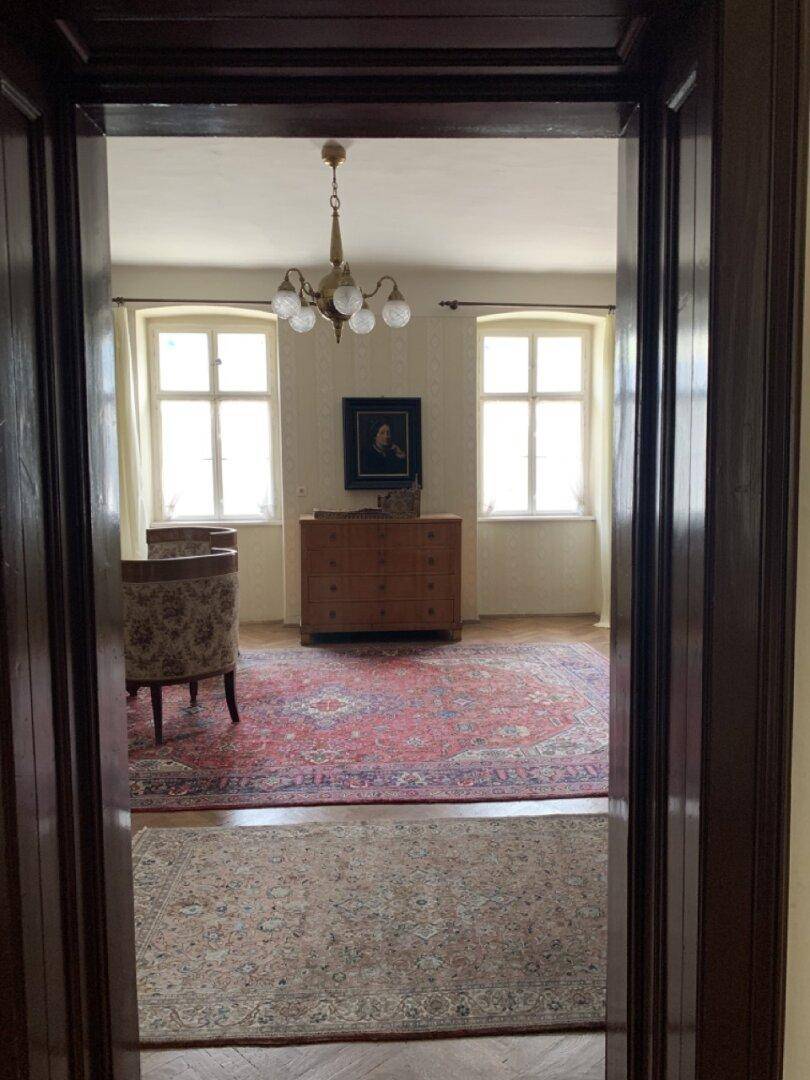 Blick durch eine Tür in einen Flur mit Teppich und einem Kronleuchter.